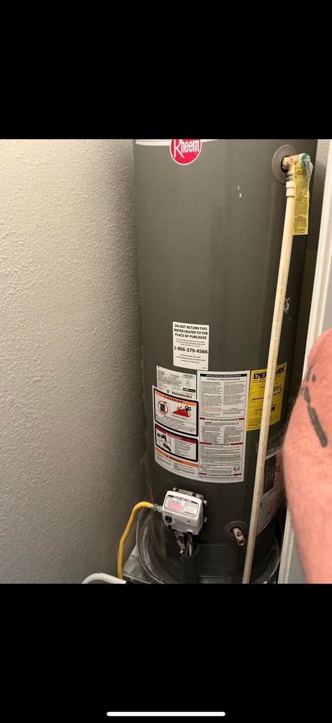 Closely cropped view of a gray water heater with labels, pipes, and wiring in a utility closet.