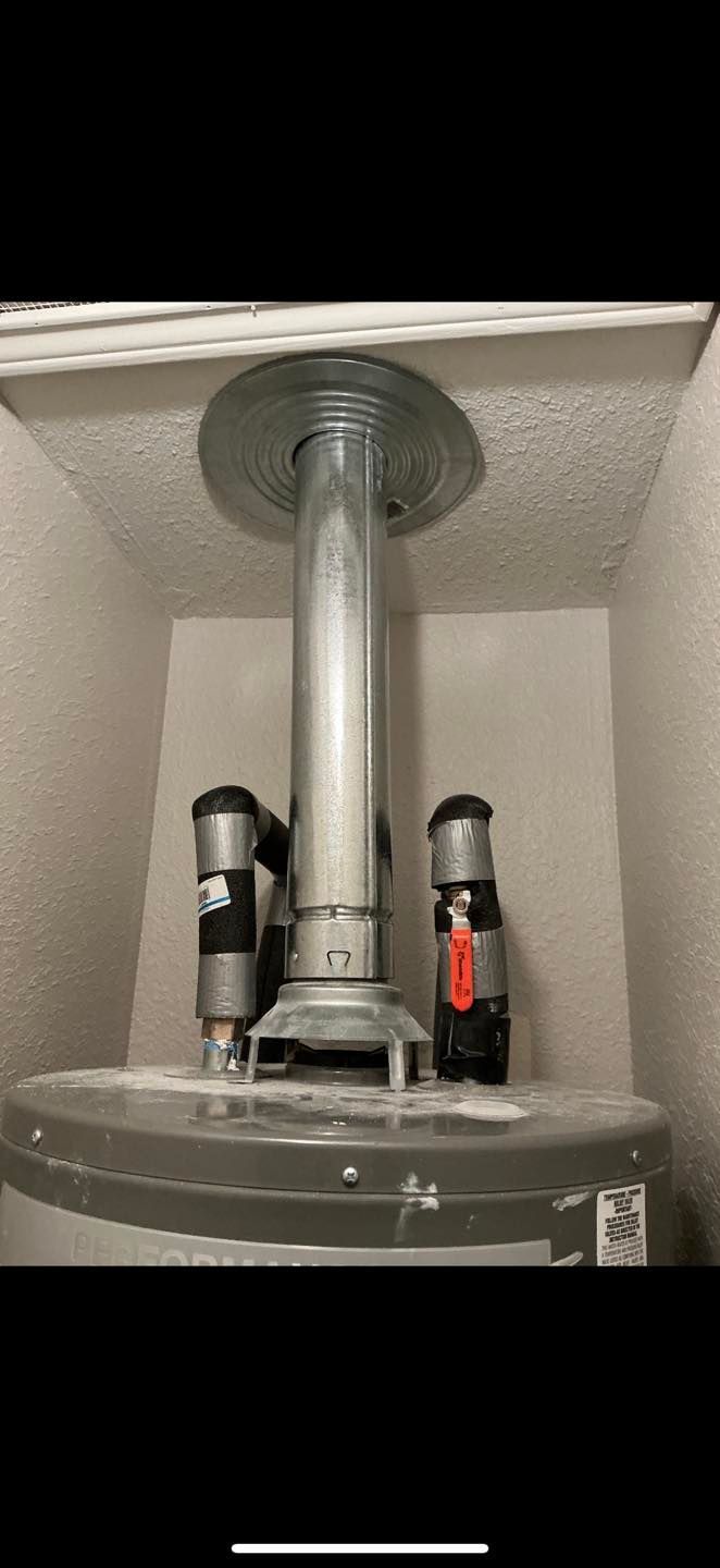 Metal vent pipe and two small devices mounted in a utility closet above a cylindrical tank