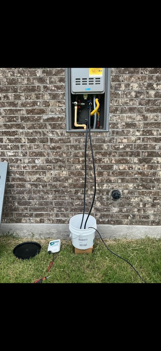 Open electrical meter box on brick wall with a cable running to a white device on the grass.