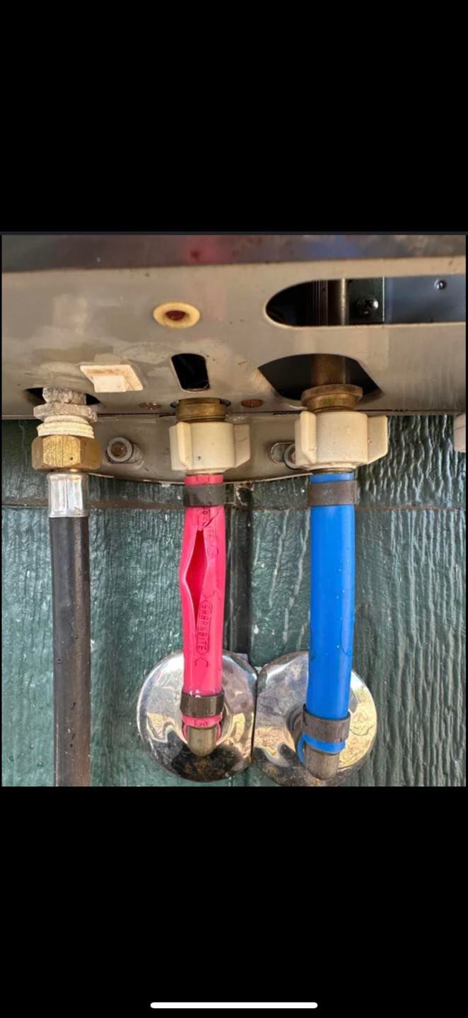 Plumbing under a sink with hot and cold water supply lines, one red and one blue, connected to shutoff valves