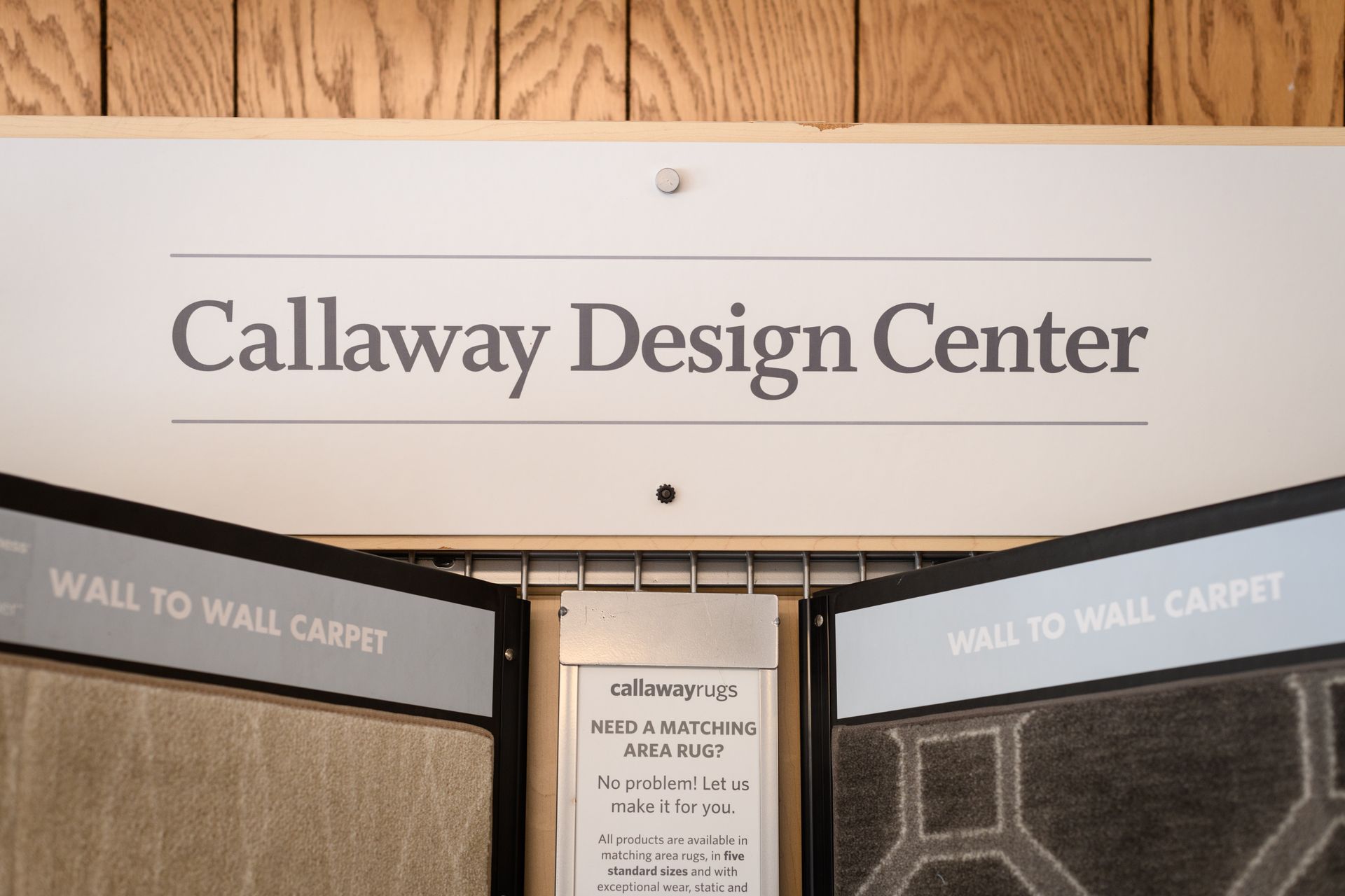 A sign for the callaway design center is hanging on a wooden wall.