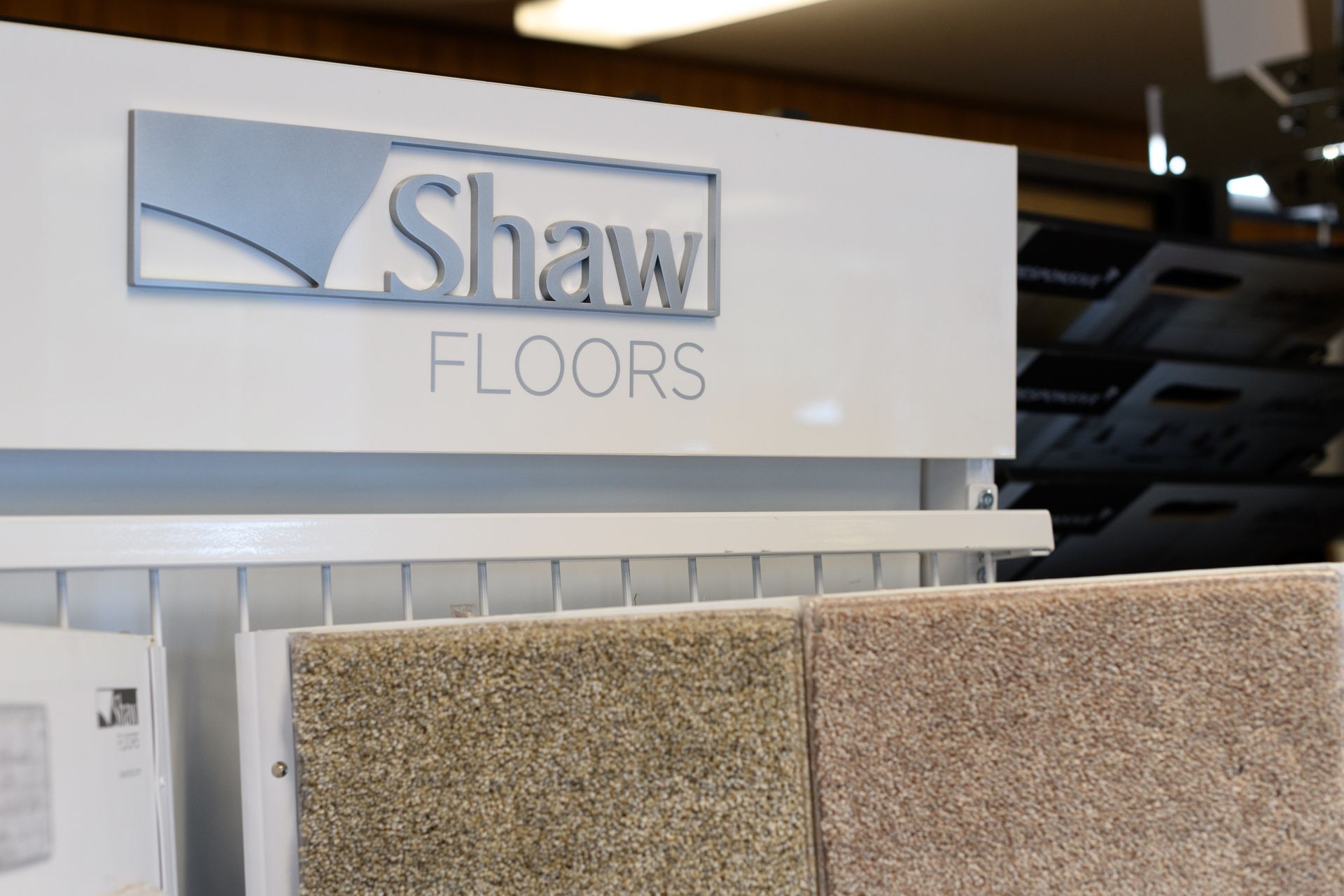 A shaw floors sign is above a display of carpets