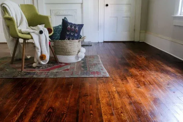 A living room with a wooden floor , a chair , a basket of pillows and a rug. A living room with a wooden floor , a chair , a basket of pillows and a rug.