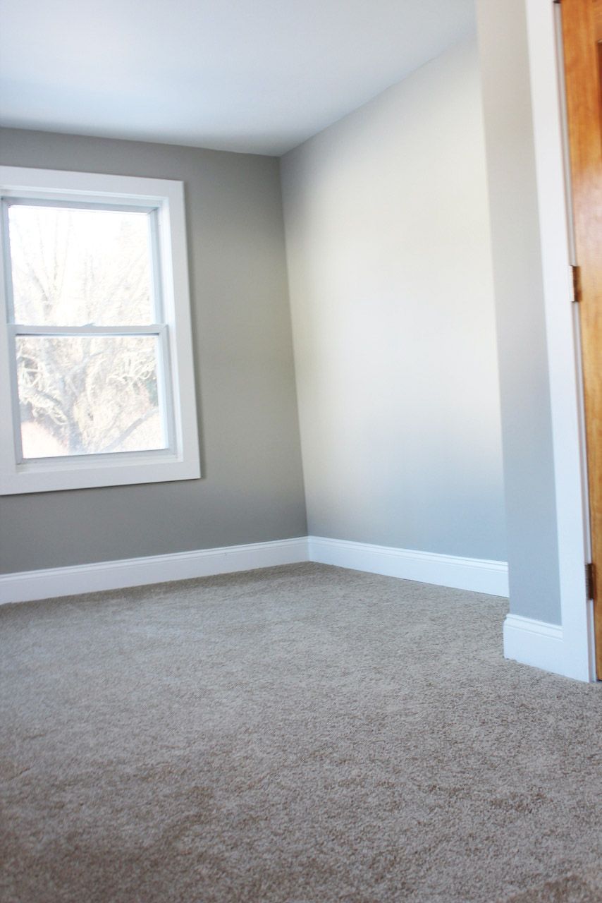 An empty room with a window and a carpeted floor