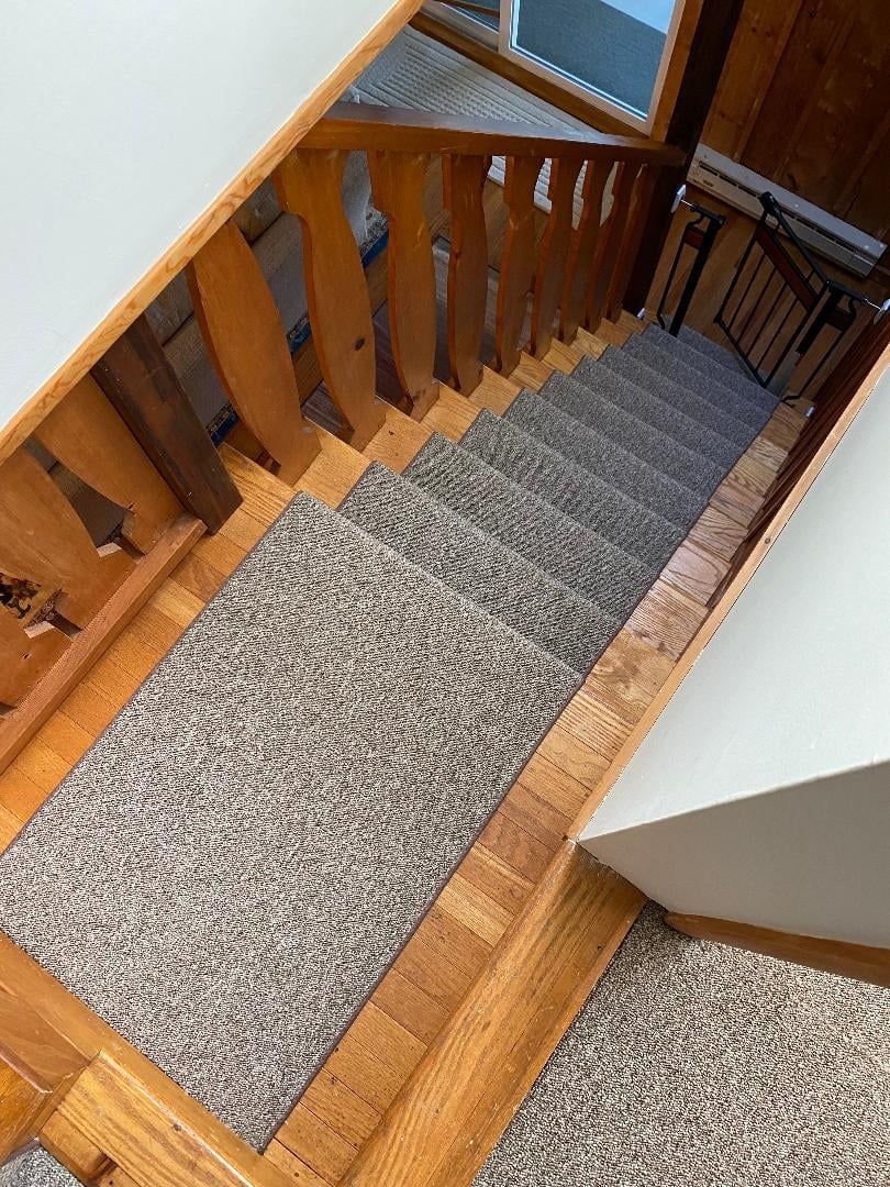 A staircase with a wooden railing and a carpeted staircase.