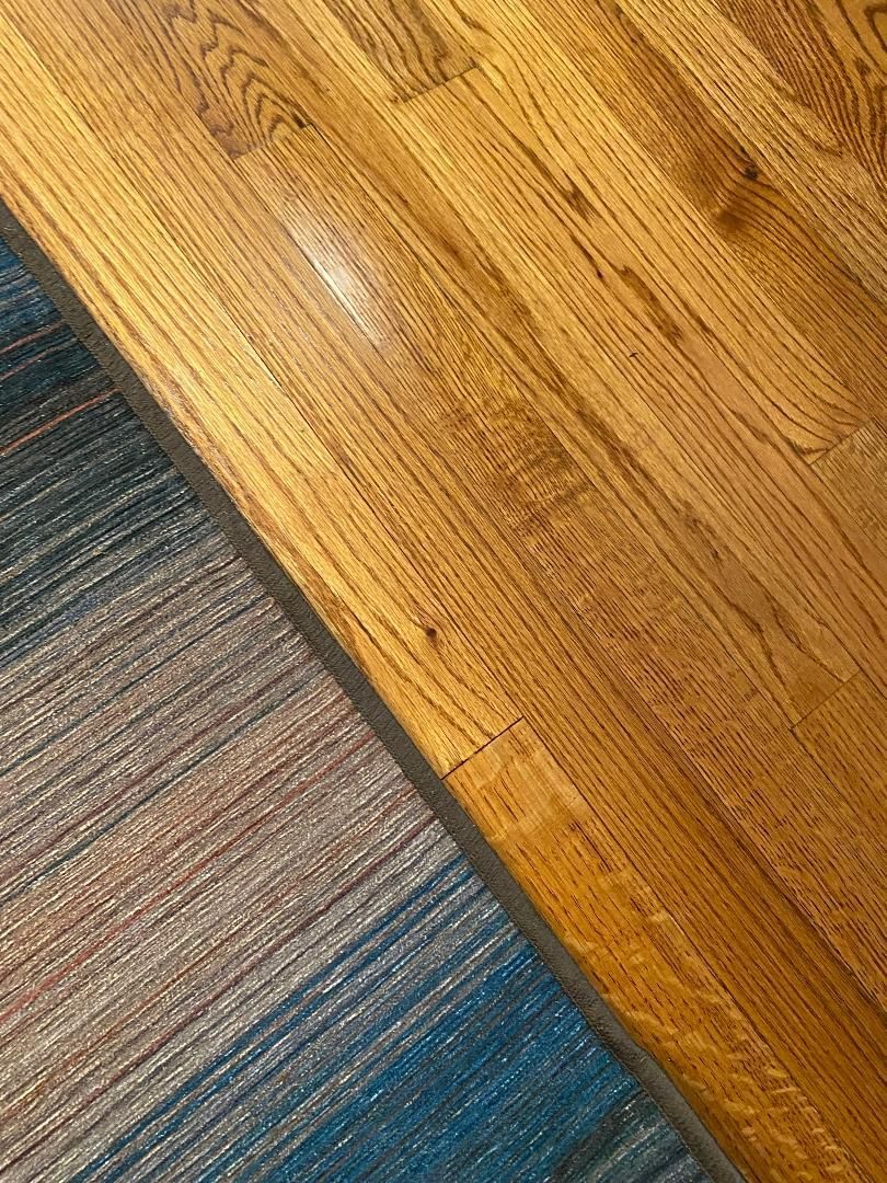 A close up of a wooden floor next to a rug.