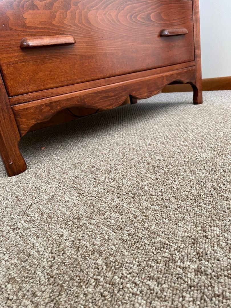 A wooden dresser is sitting on top of a carpeted floor.