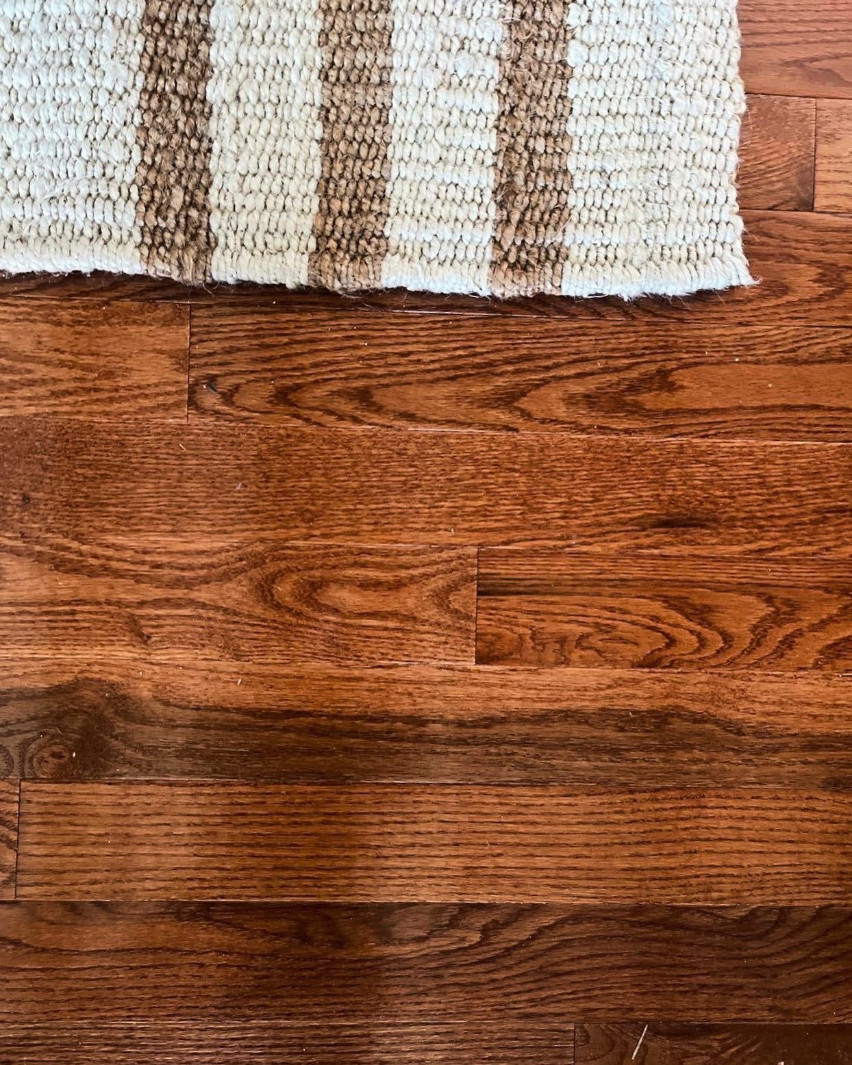 A close up of a wooden floor with a rug on it.