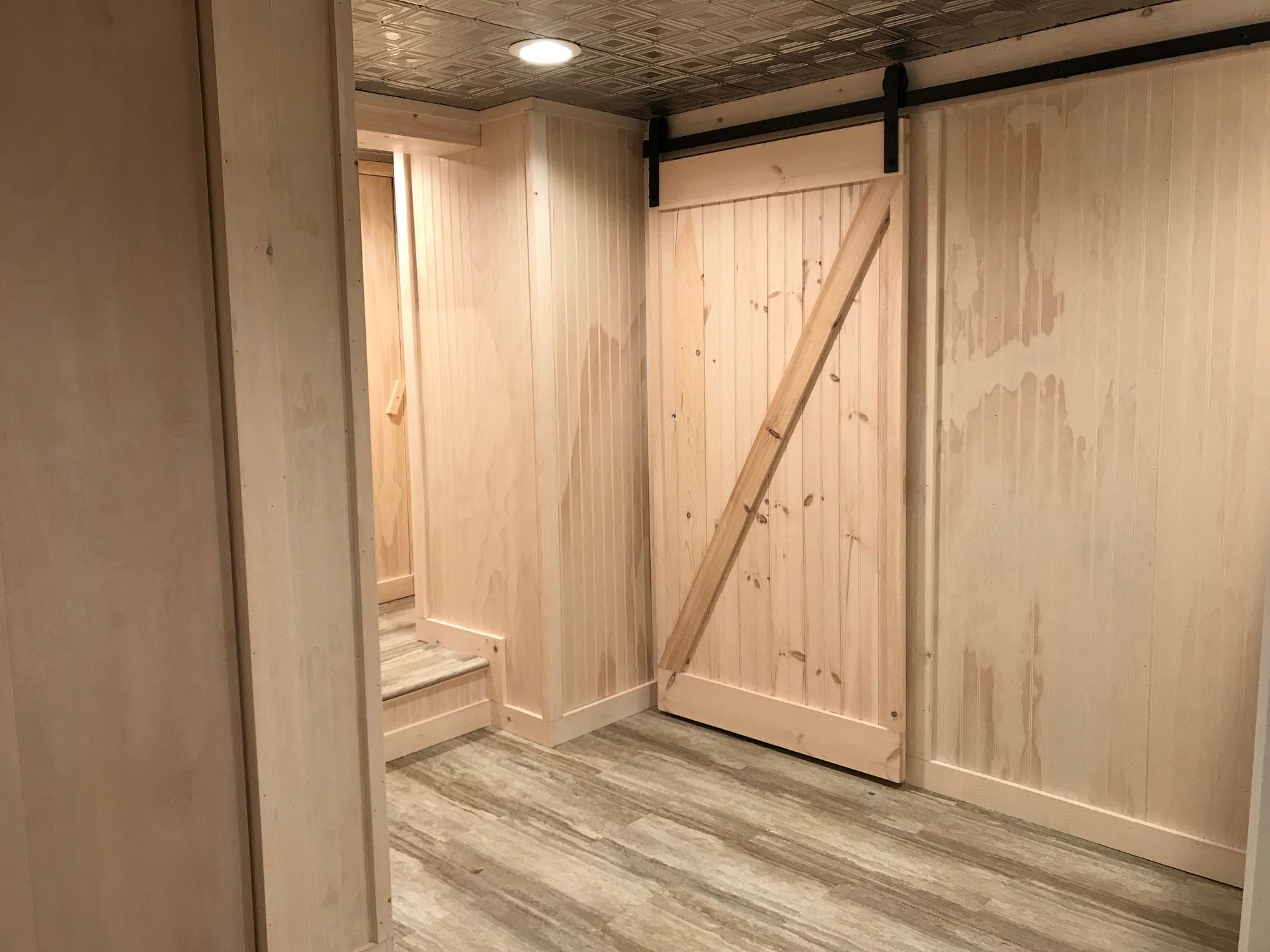 A room with a sliding barn door and stairs.