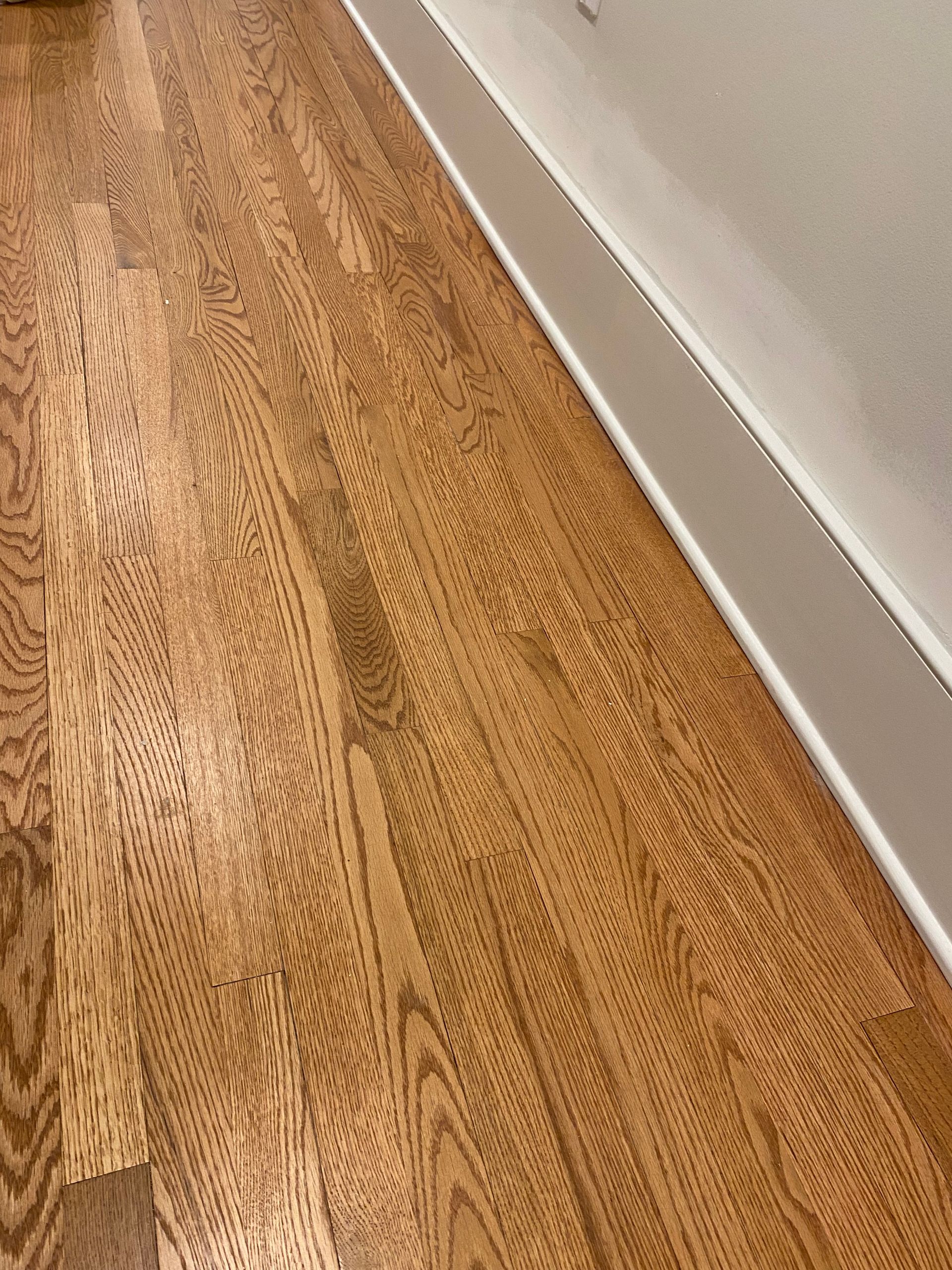 A close up of a wooden floor in a room with white trim.