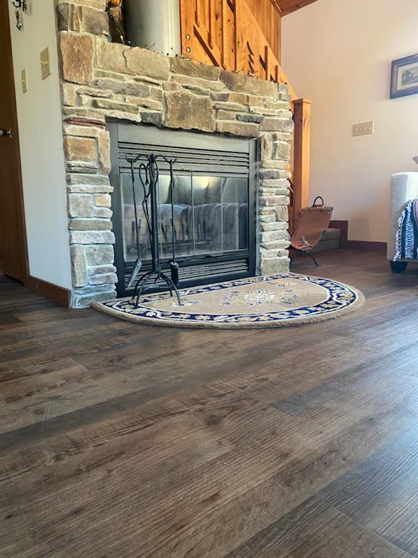 A living room with a fireplace and a rug on the floor.