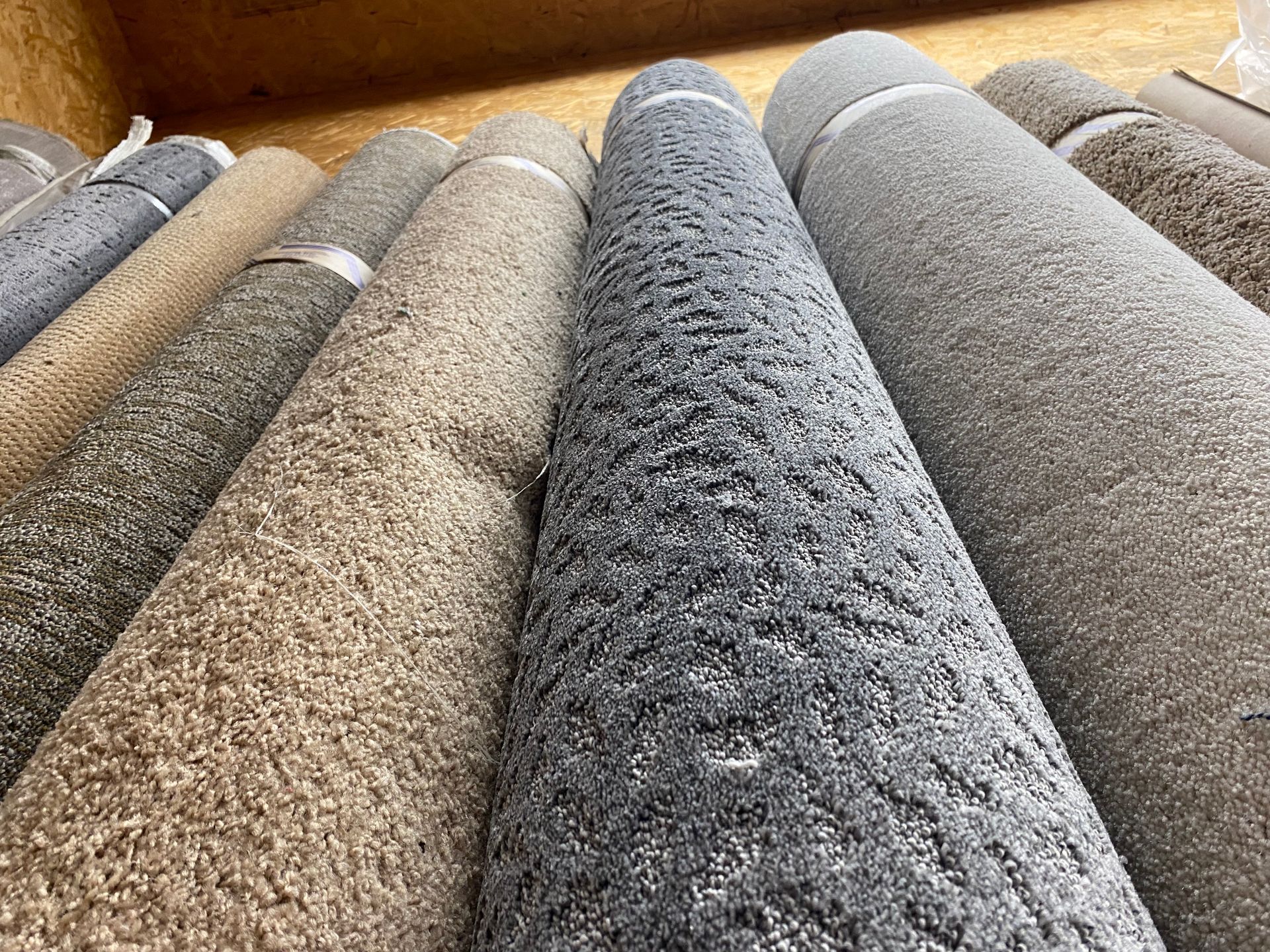 A bunch of rolls of carpet are stacked on top of each other on a wooden table.