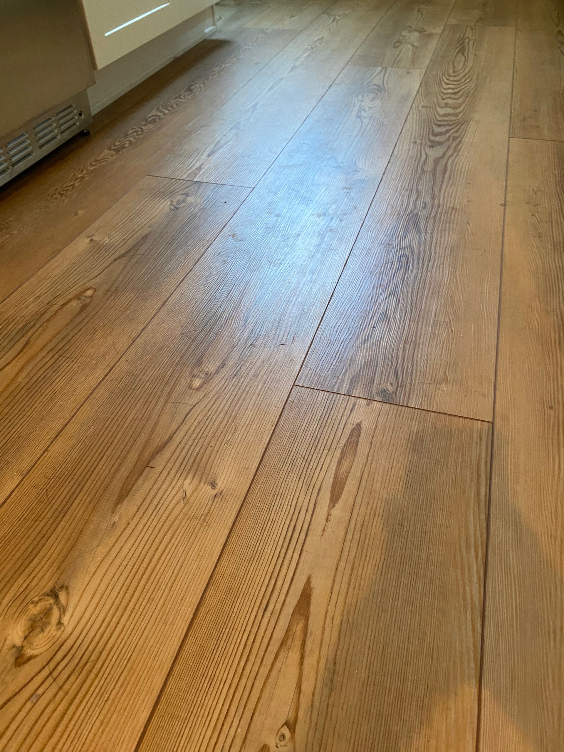A close up of a wooden floor in a kitchen.