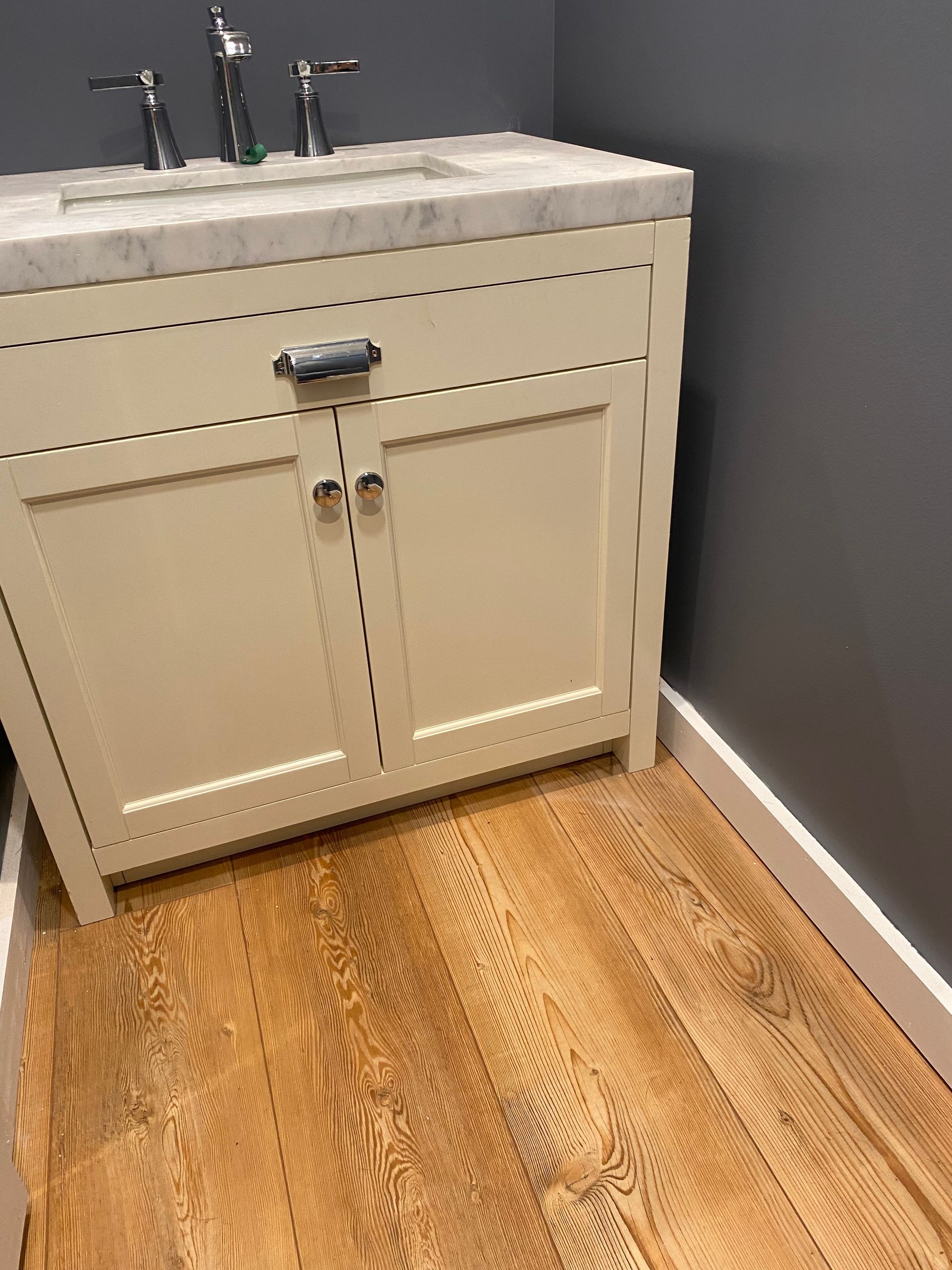 A bathroom vanity with a sink and a wooden floor.
