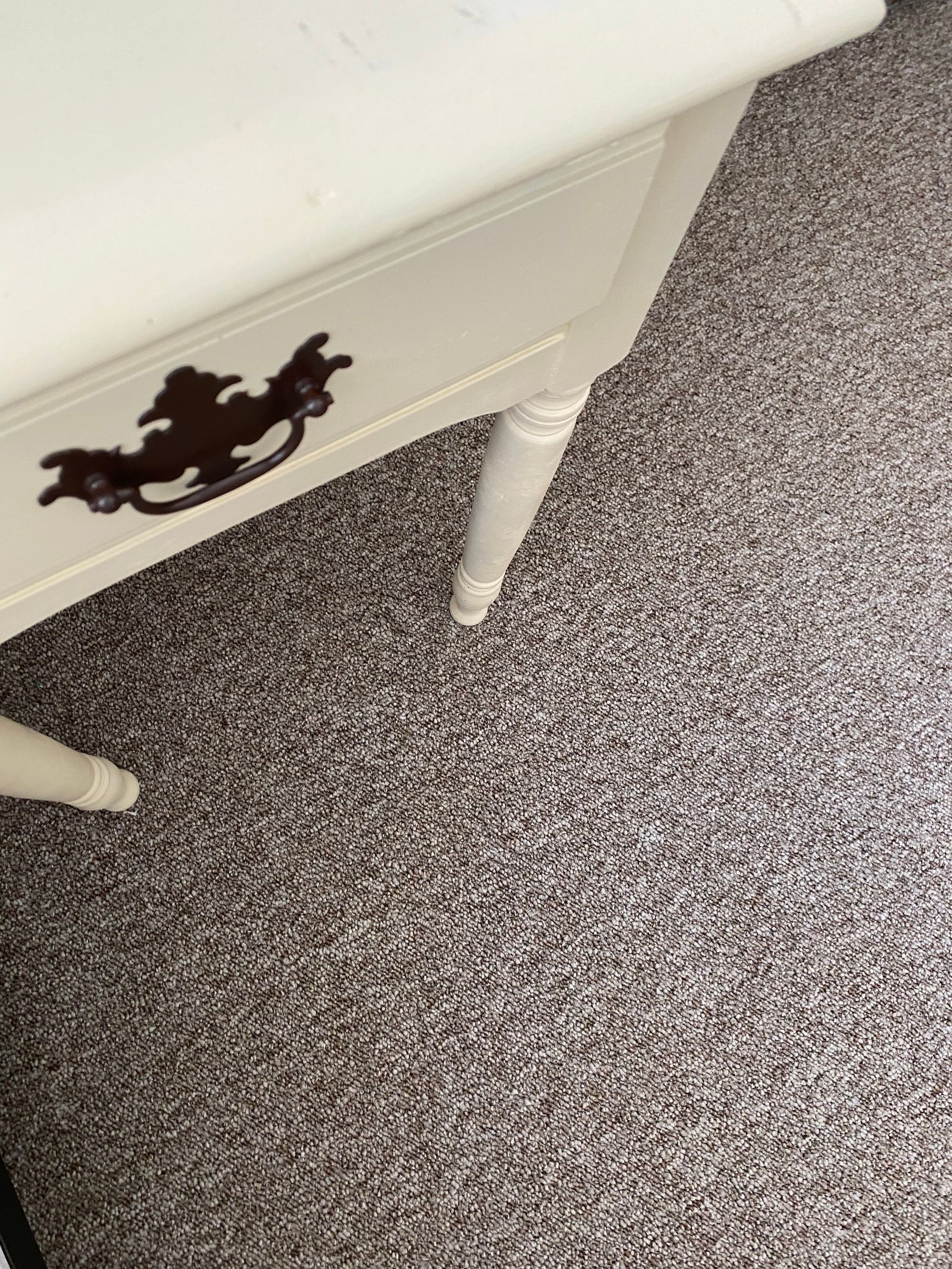 A white table with a black handle is sitting on a carpeted floor.