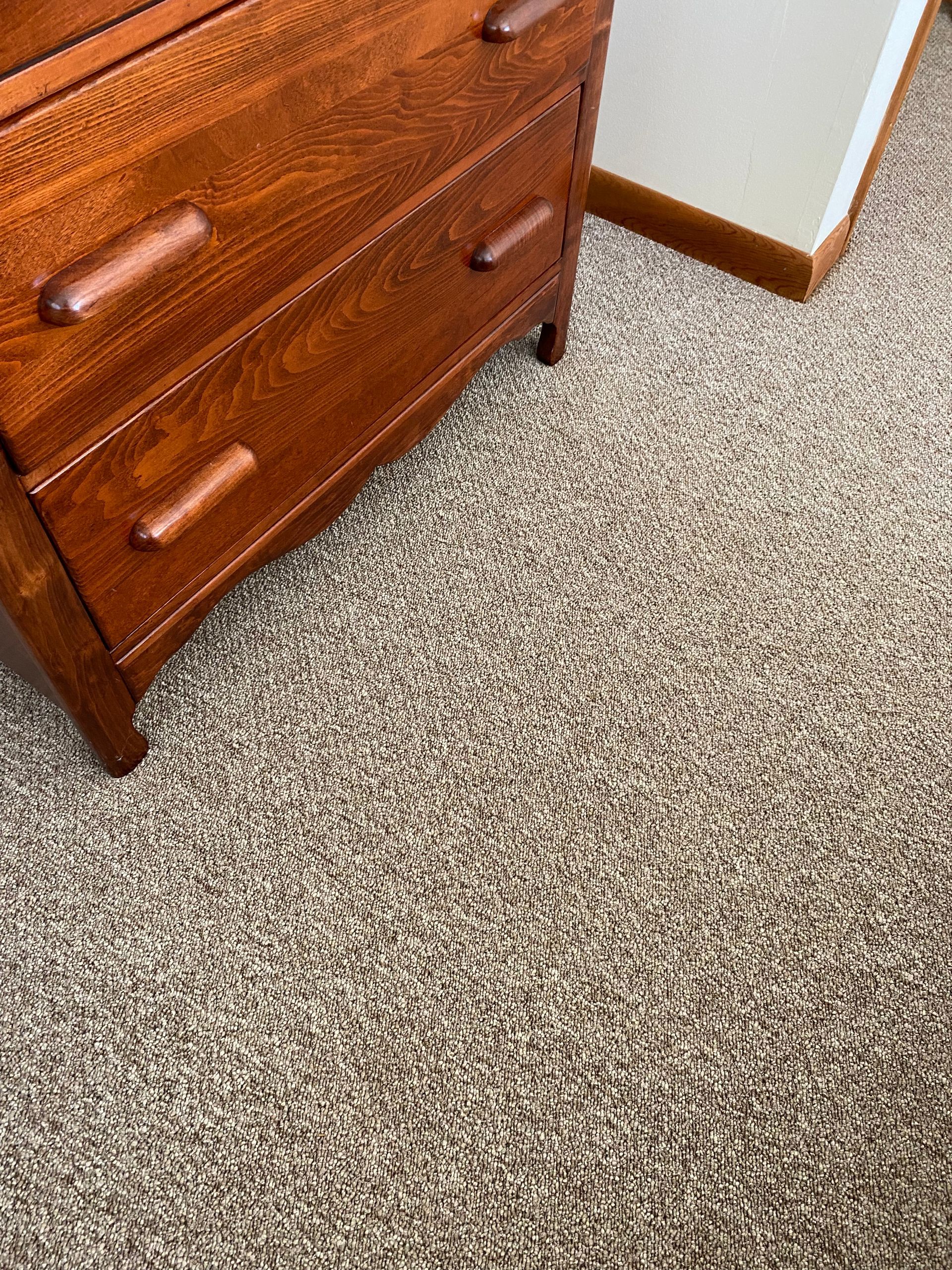 A wooden dresser is sitting on top of a carpeted floor.