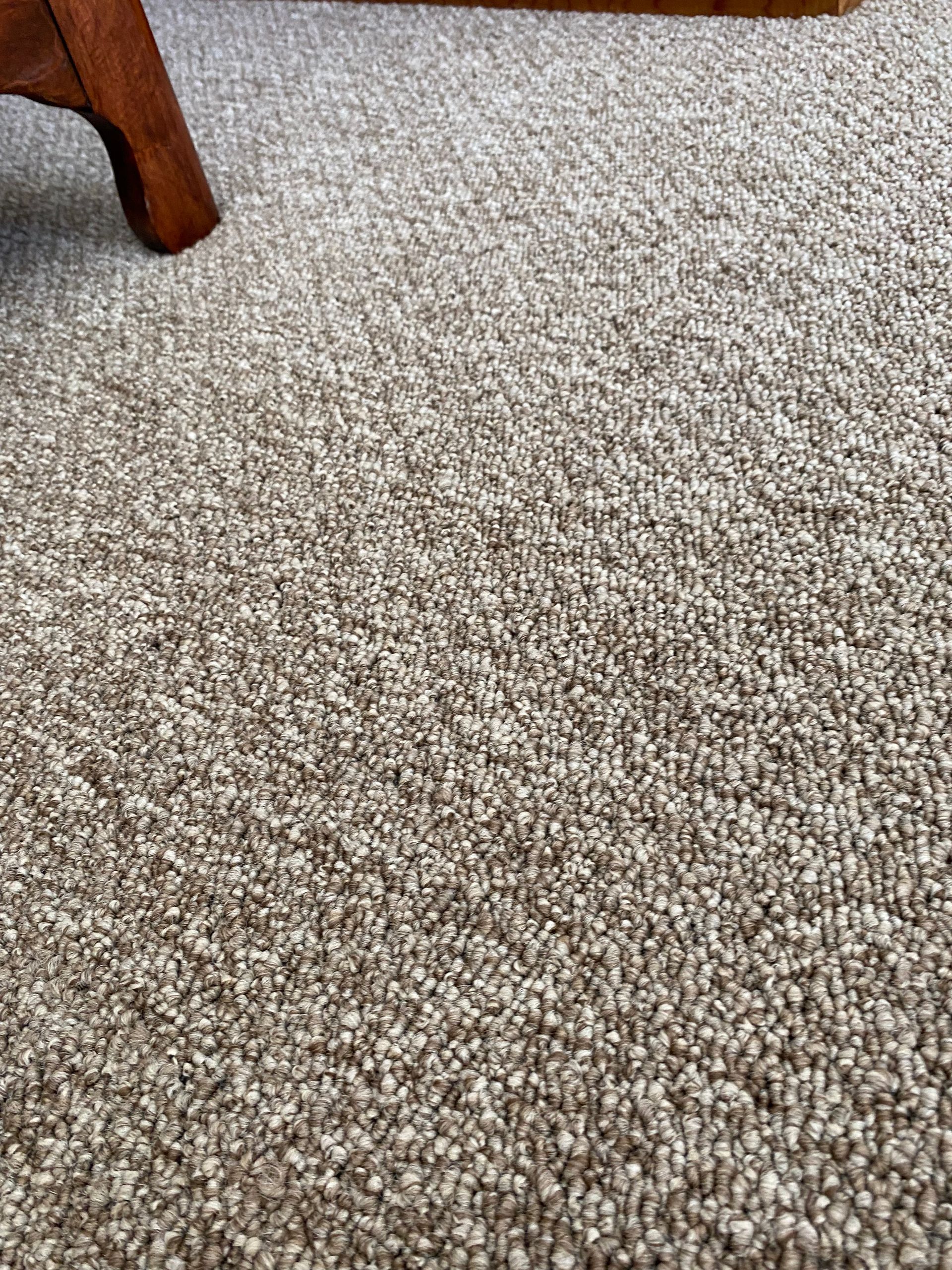 A close up of a carpet with a chair in the background.