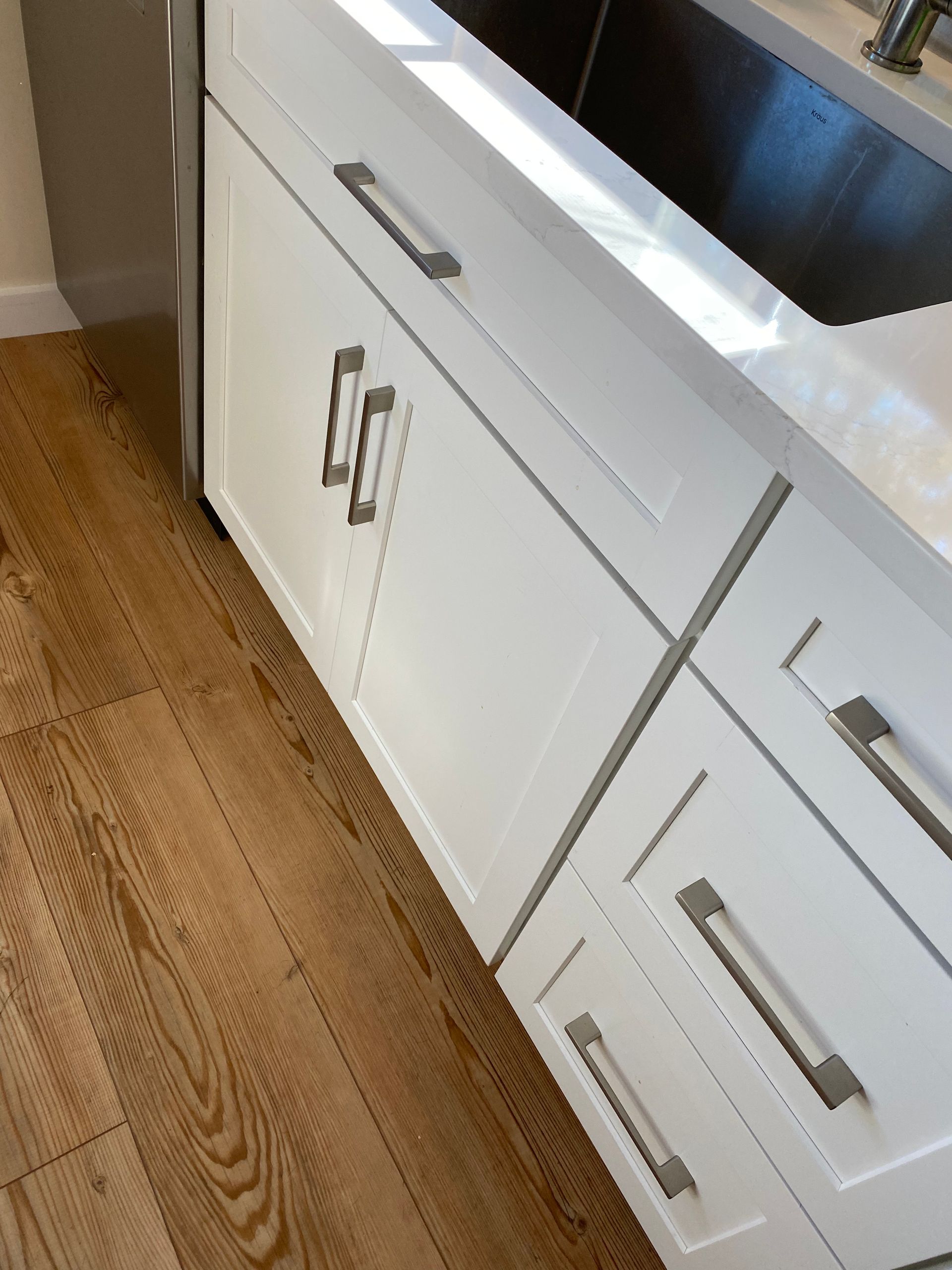 A kitchen with white cabinets and a stainless steel sink