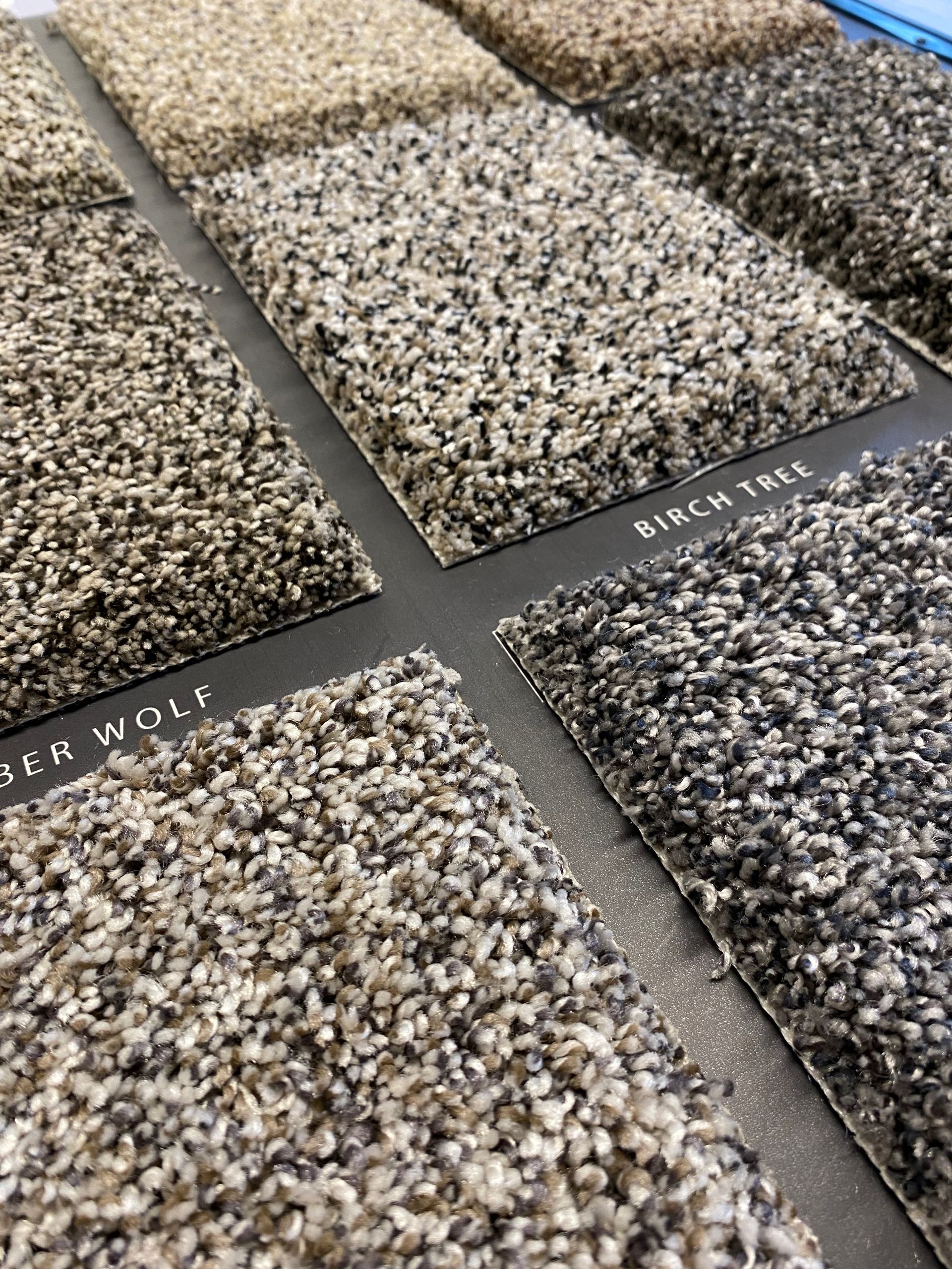 A variety of carpet samples are lined up on a table.