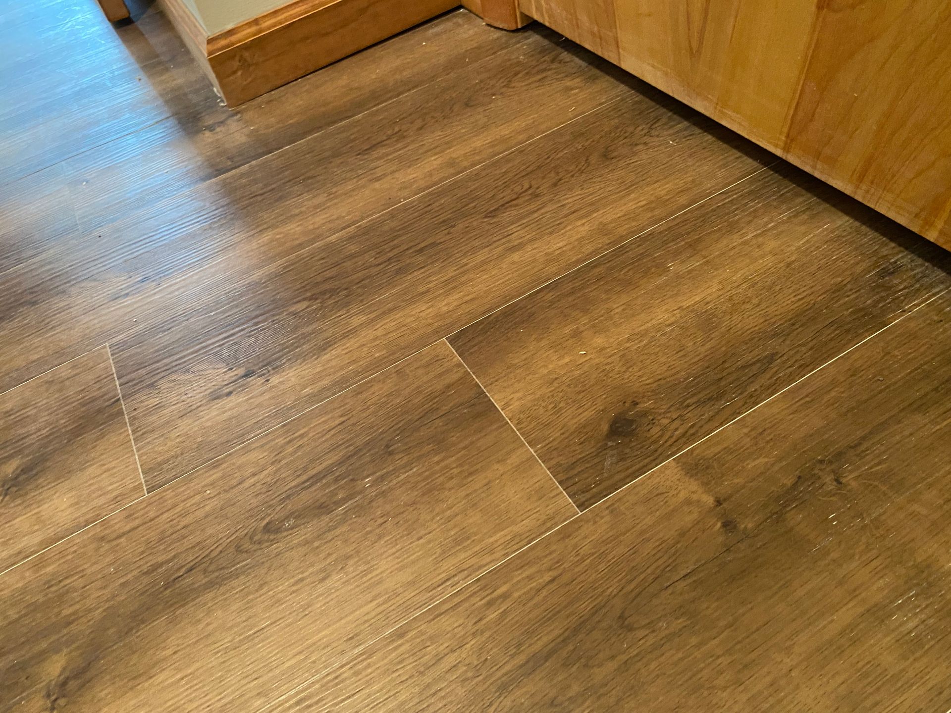A close up of a wooden floor in a kitchen.