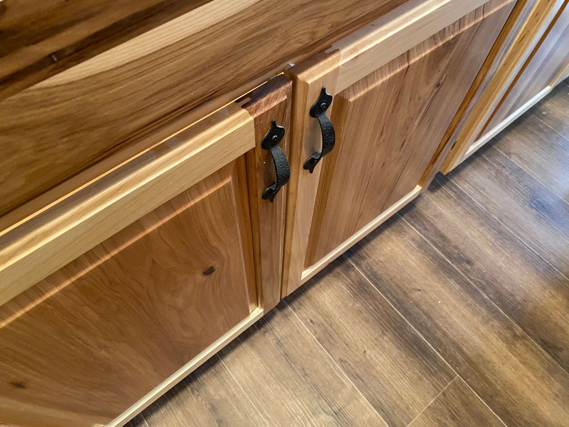A close up of a wooden cabinet with black handles.