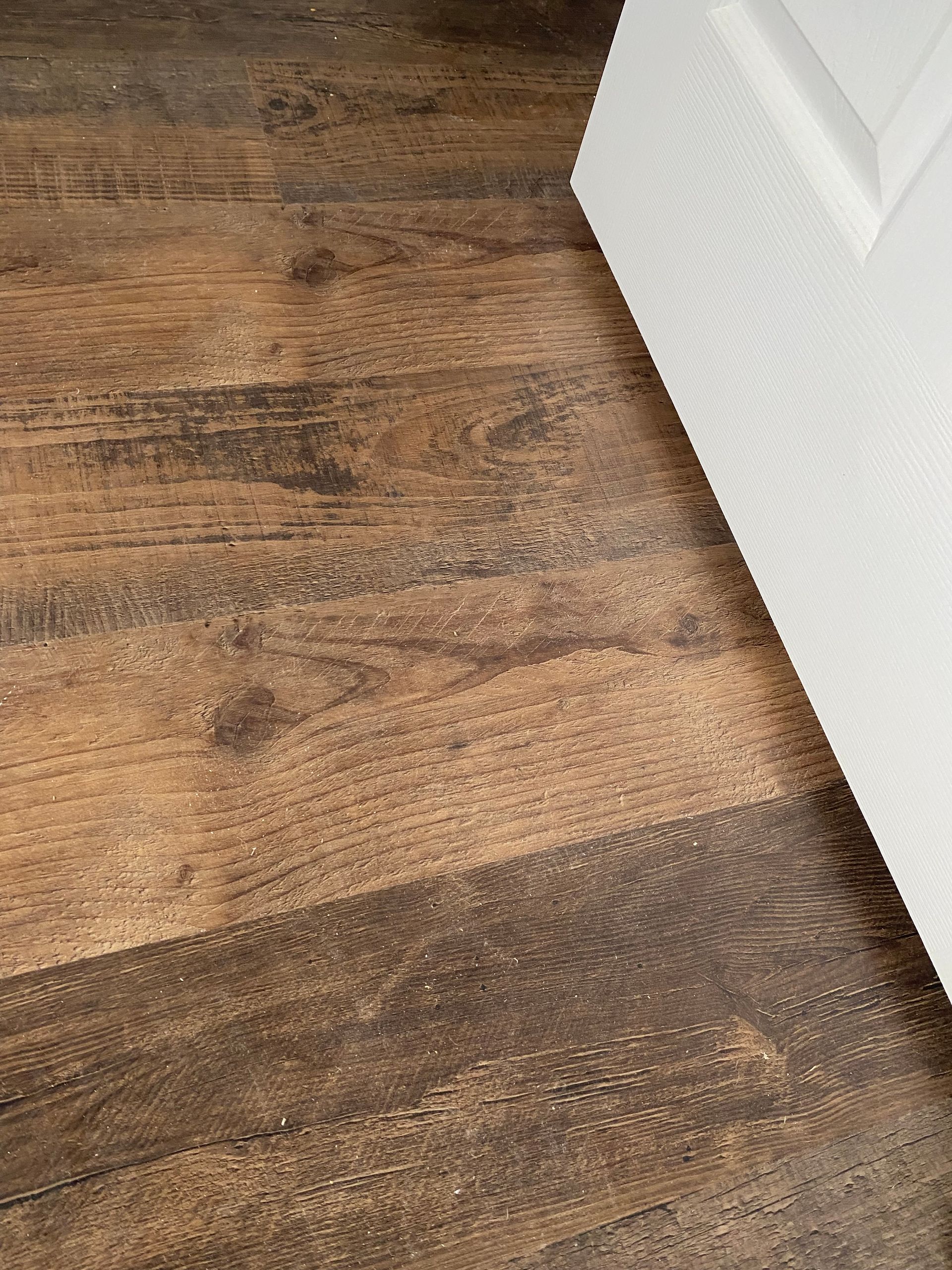 A close up of a wooden floor next to a white door.