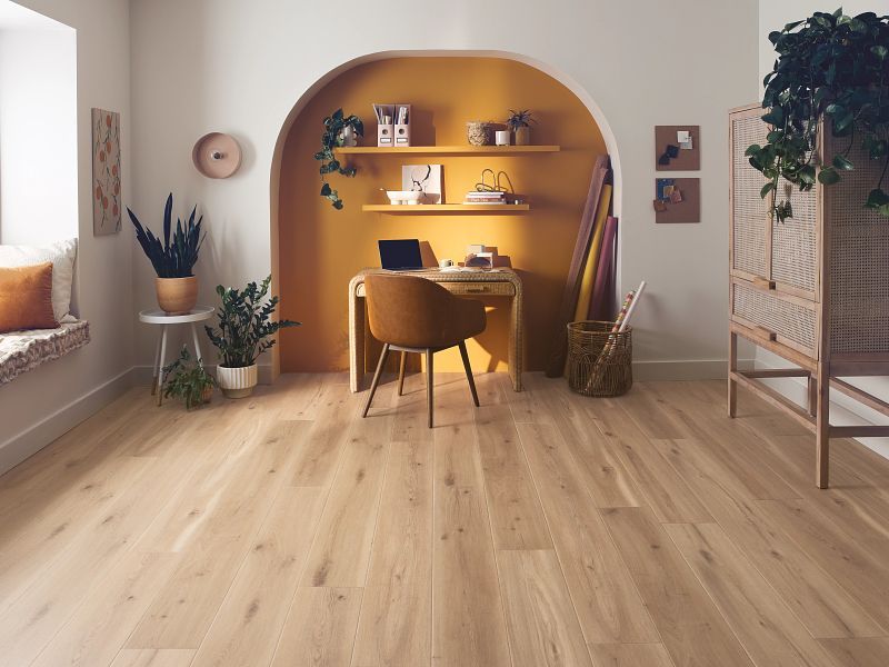 A living room with hardwood floors and a desk with a laptop on it.