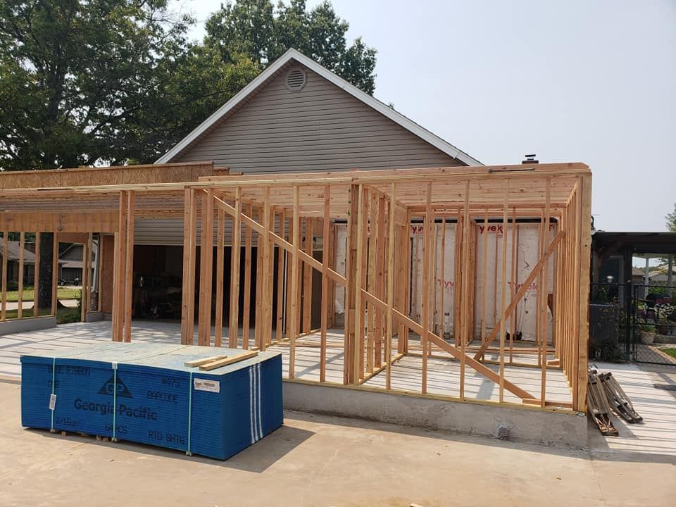 A house is being built with wooden beams and a blue box in front of it.