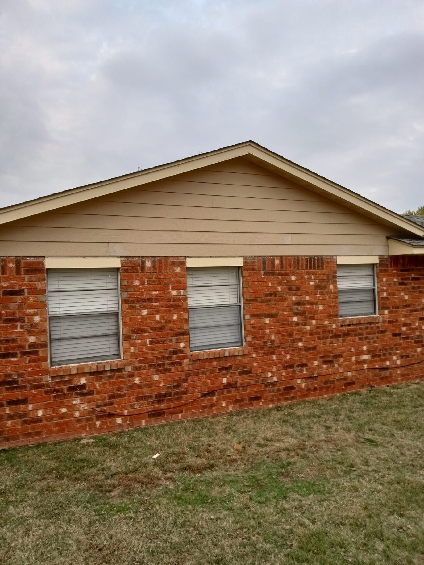 A brick house with three windows and a roof.