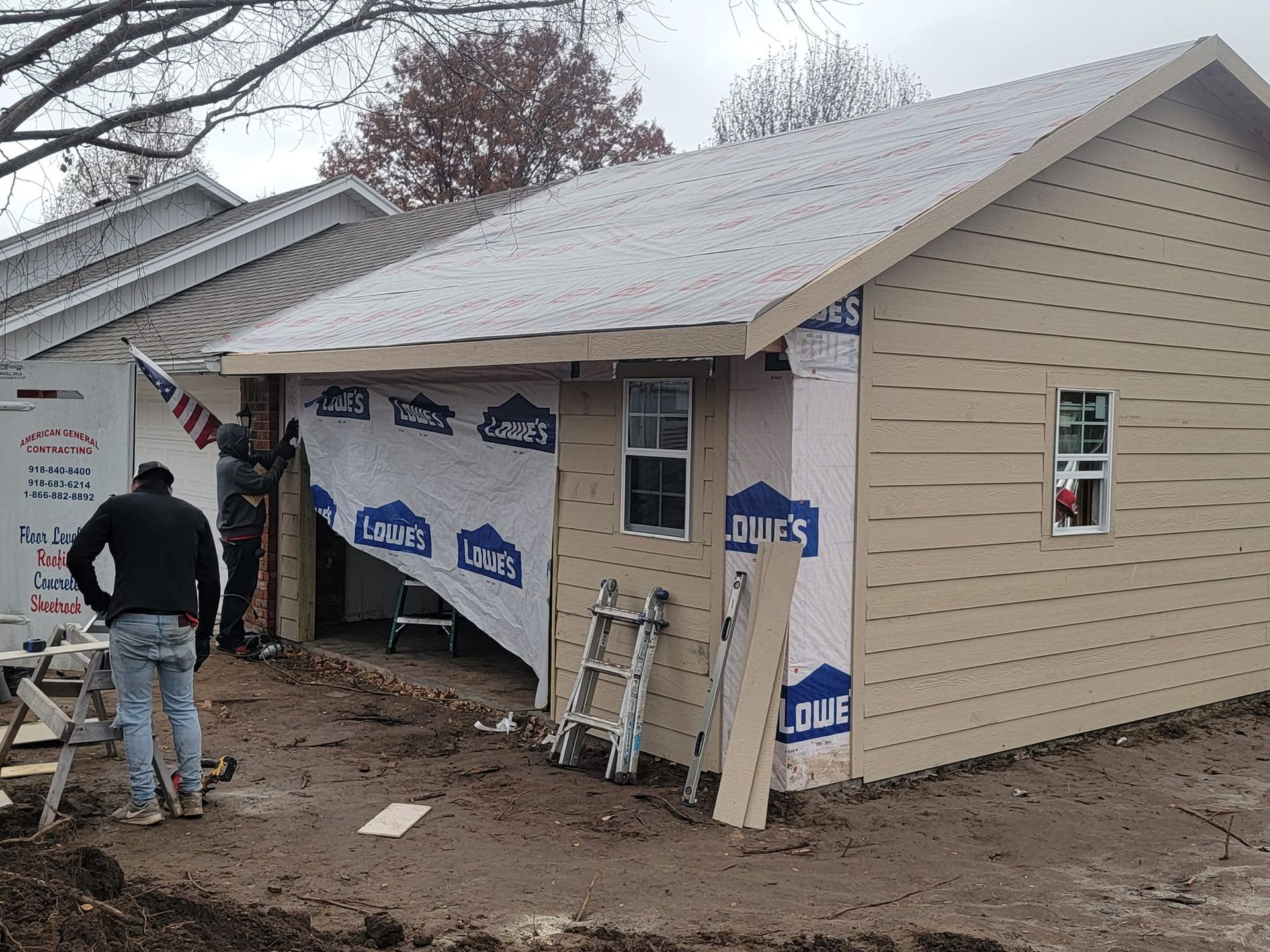 A man is standing in front of a house that is being remodeled.