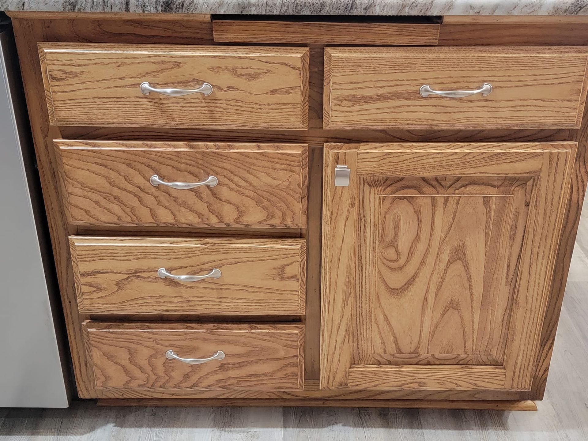 A wooden cabinet with drawers and a door in a kitchen.