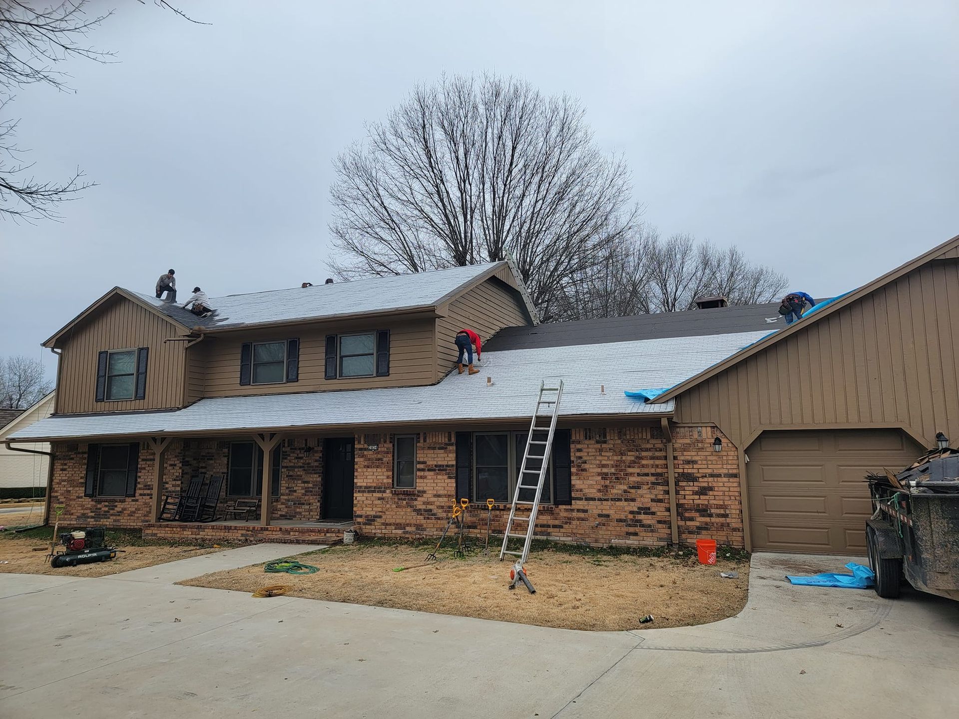 A couple of people are working on the roof of a house.