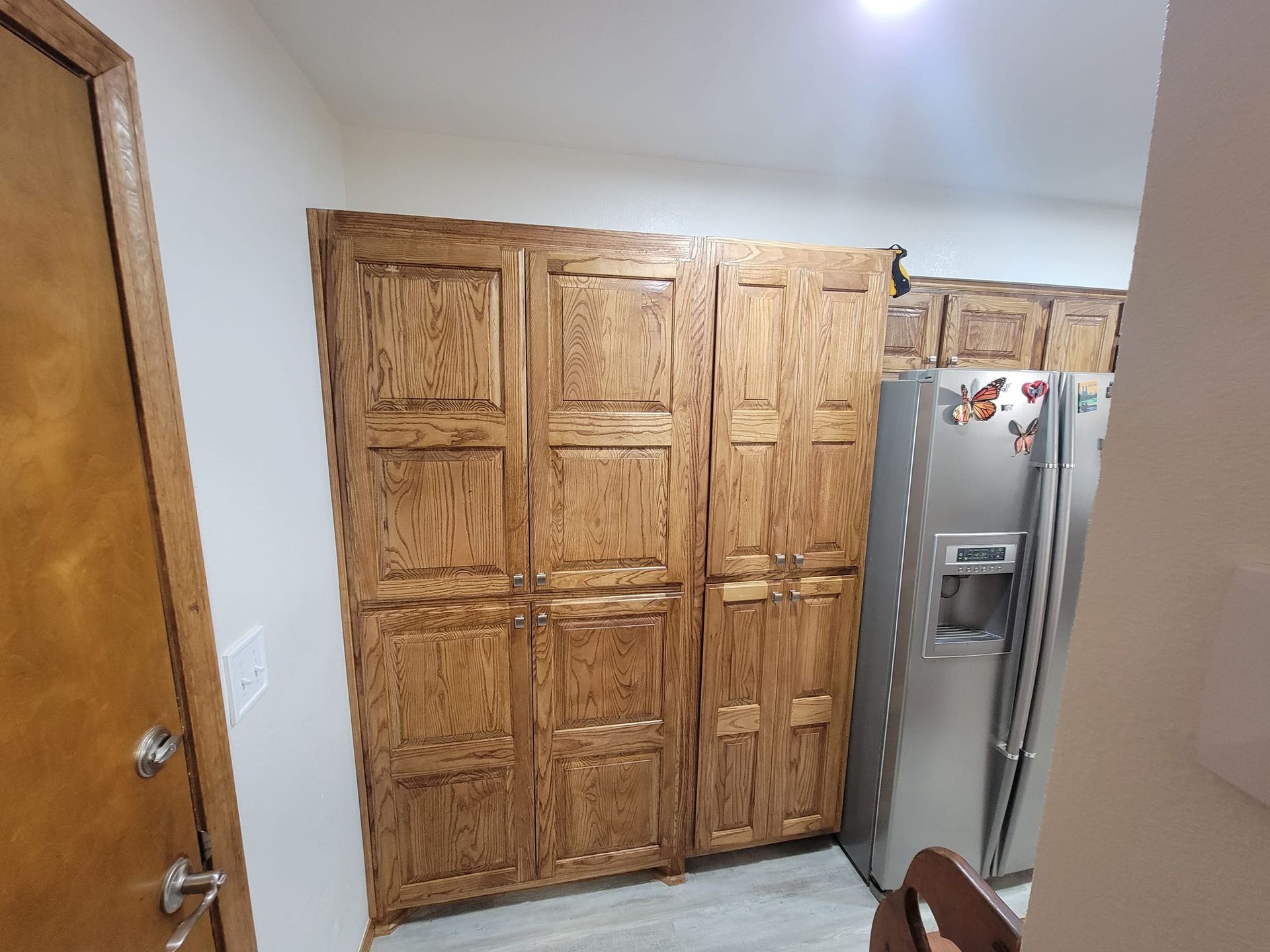 A kitchen with wooden cabinets and a stainless steel refrigerator.