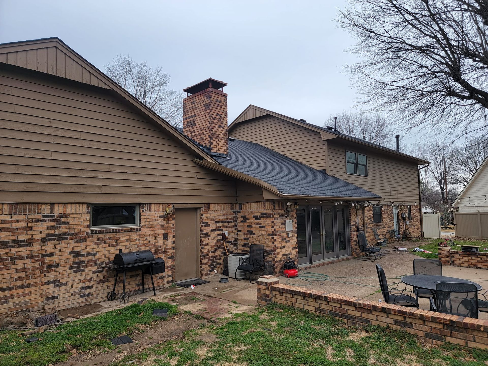 A large brick house with a patio and a bbq in the backyard.