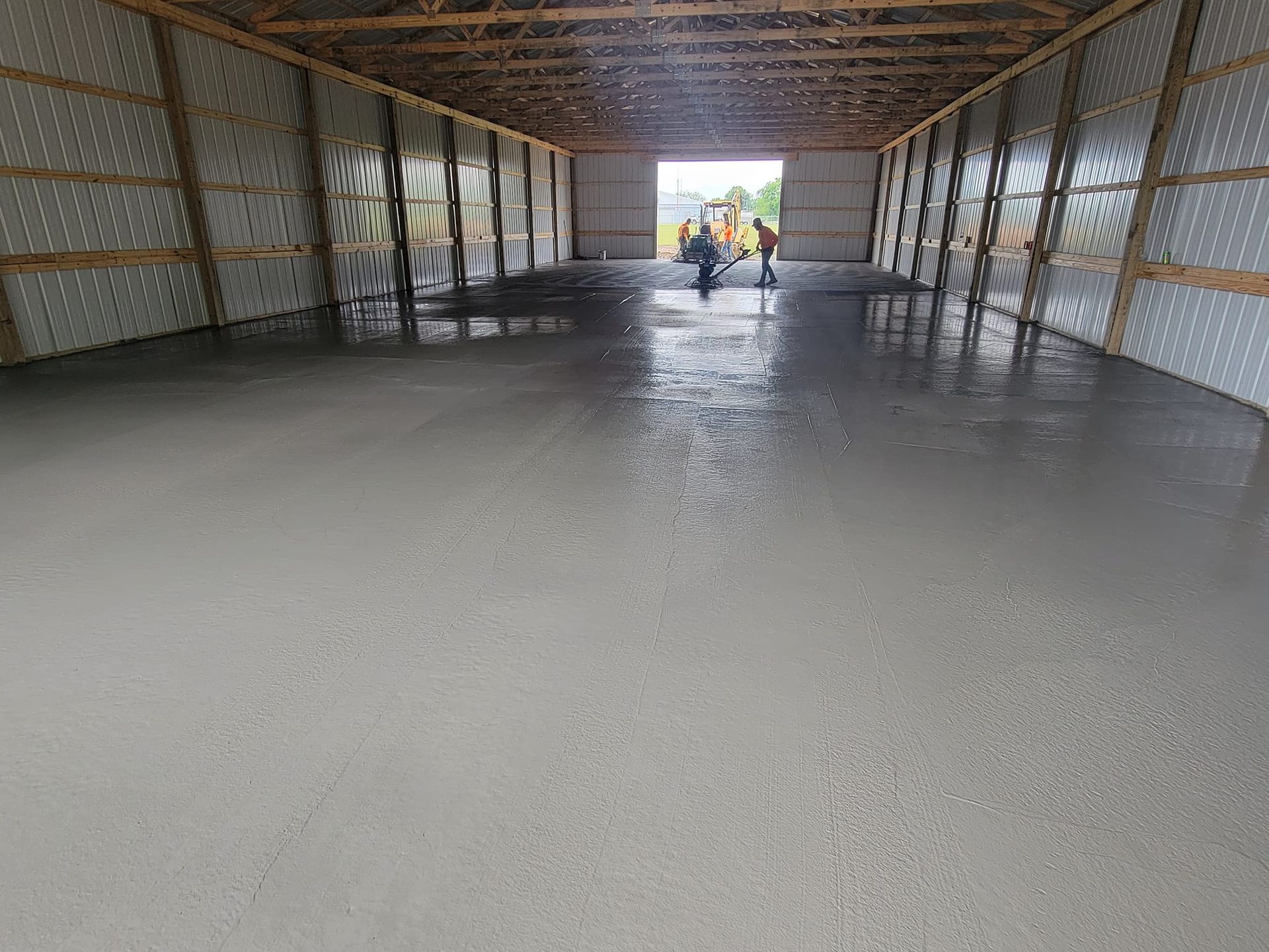 A group of people are standing inside of a building with a concrete floor.