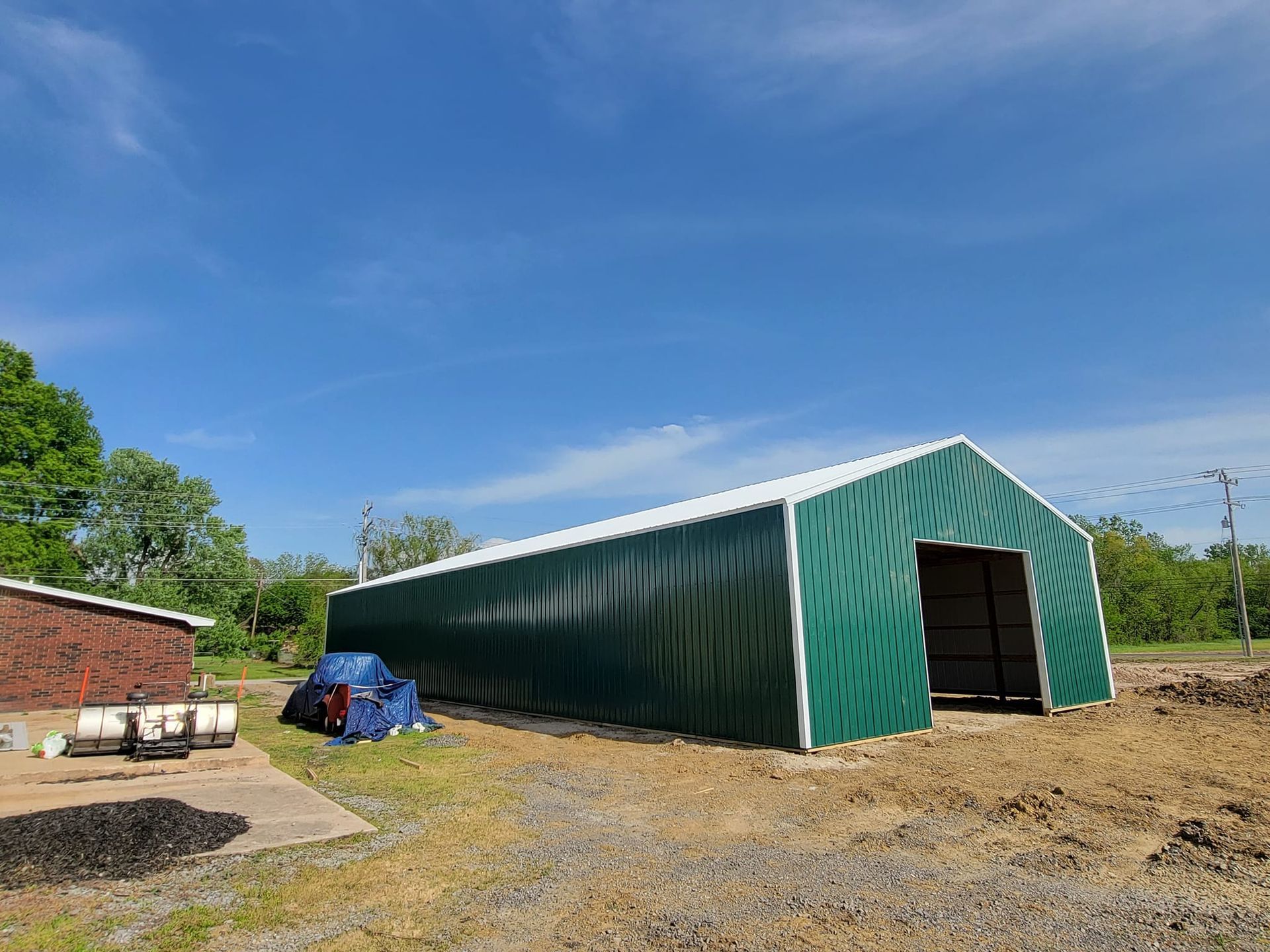 A large green building is sitting in the middle of a dirt field.