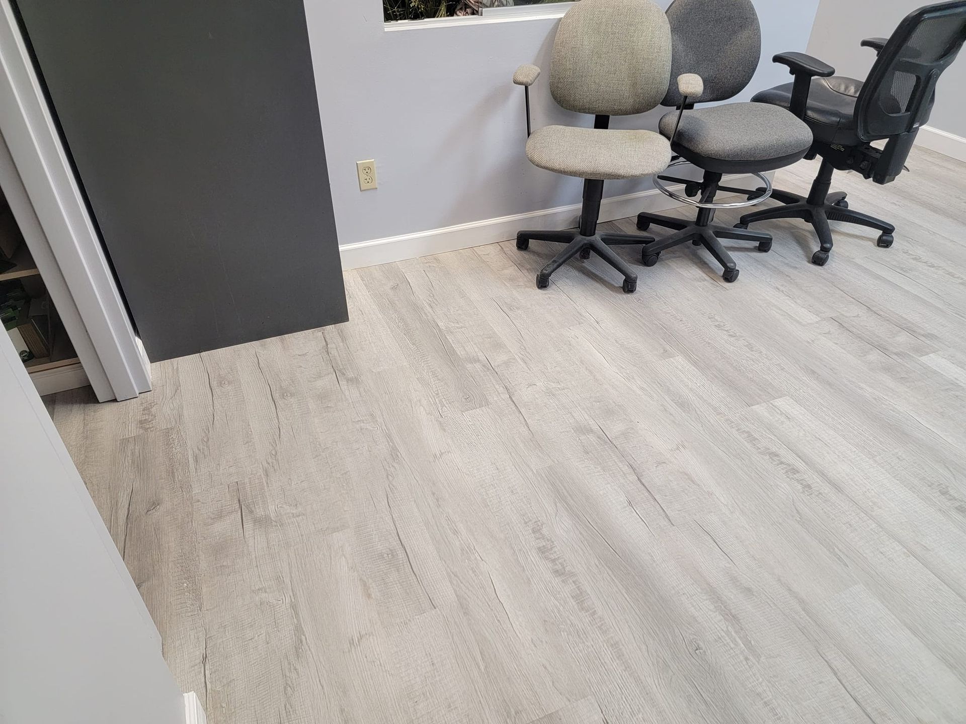 Three office chairs are sitting on a wooden floor in a room.