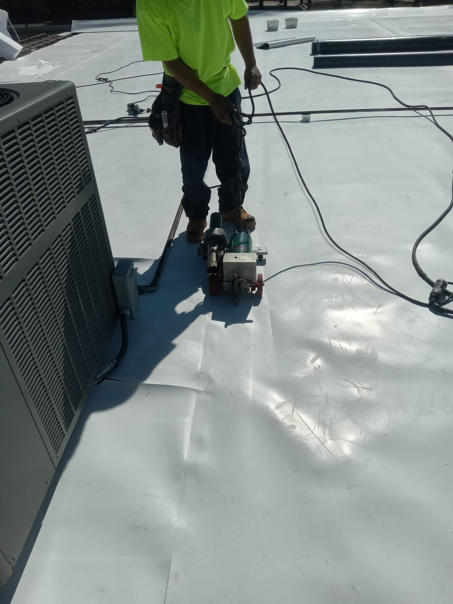 A man is working on a roof with a machine.