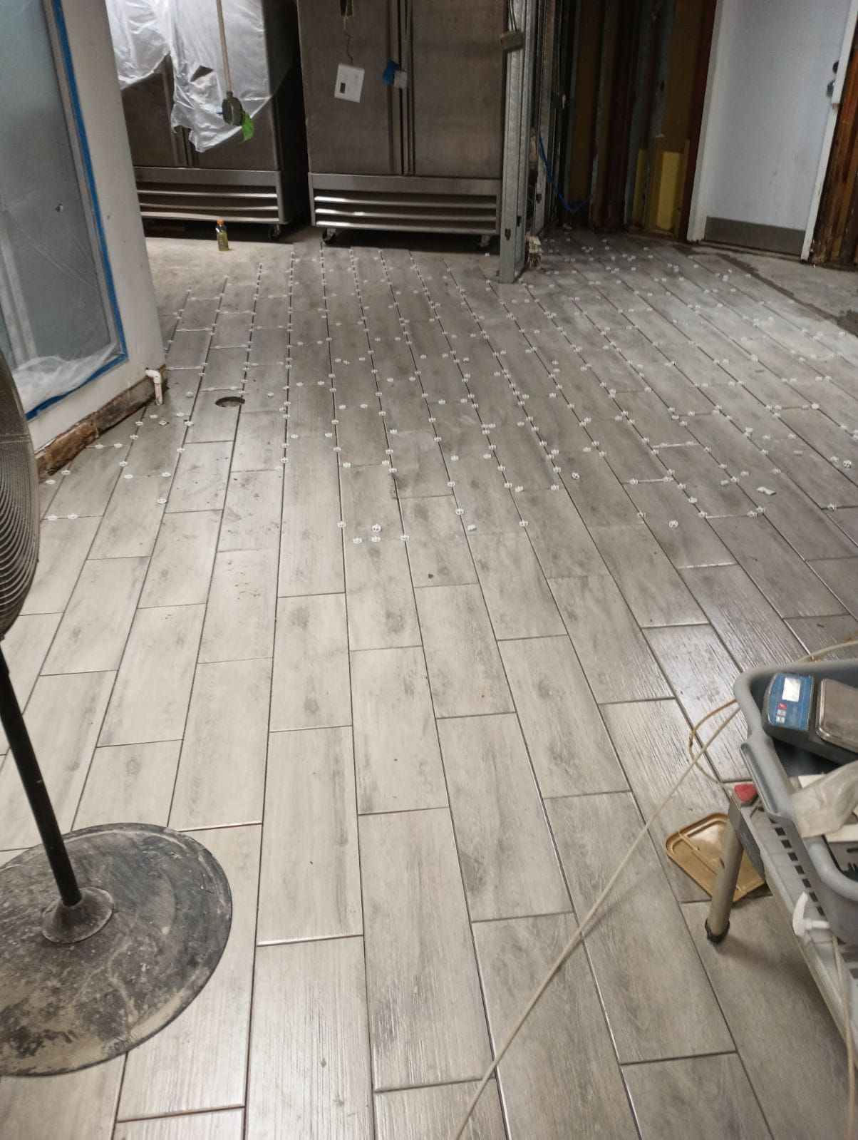 A room with a wooden floor and a stainless steel refrigerator.