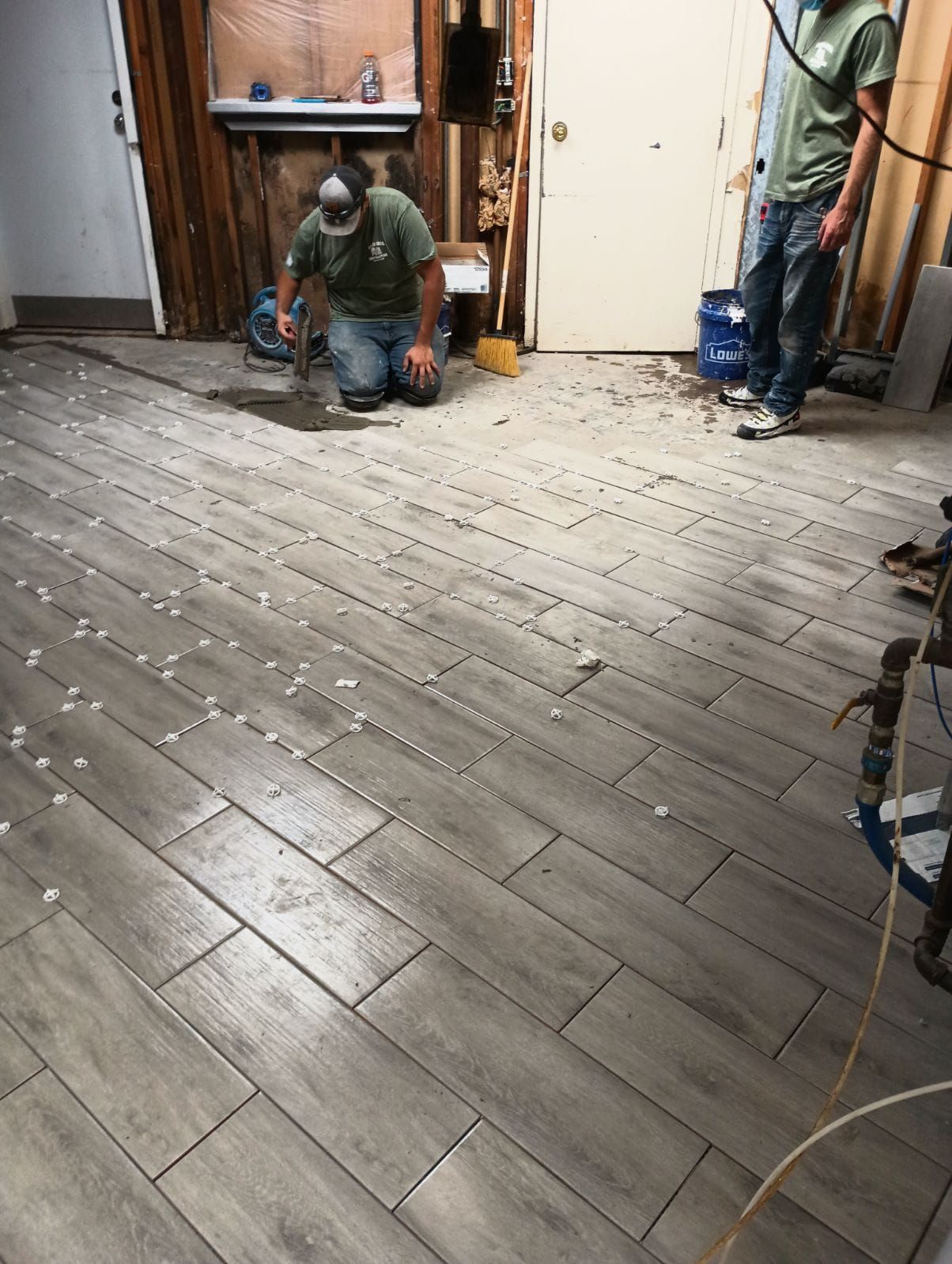 A man is kneeling on the floor in a room with a vacuum cleaner.
