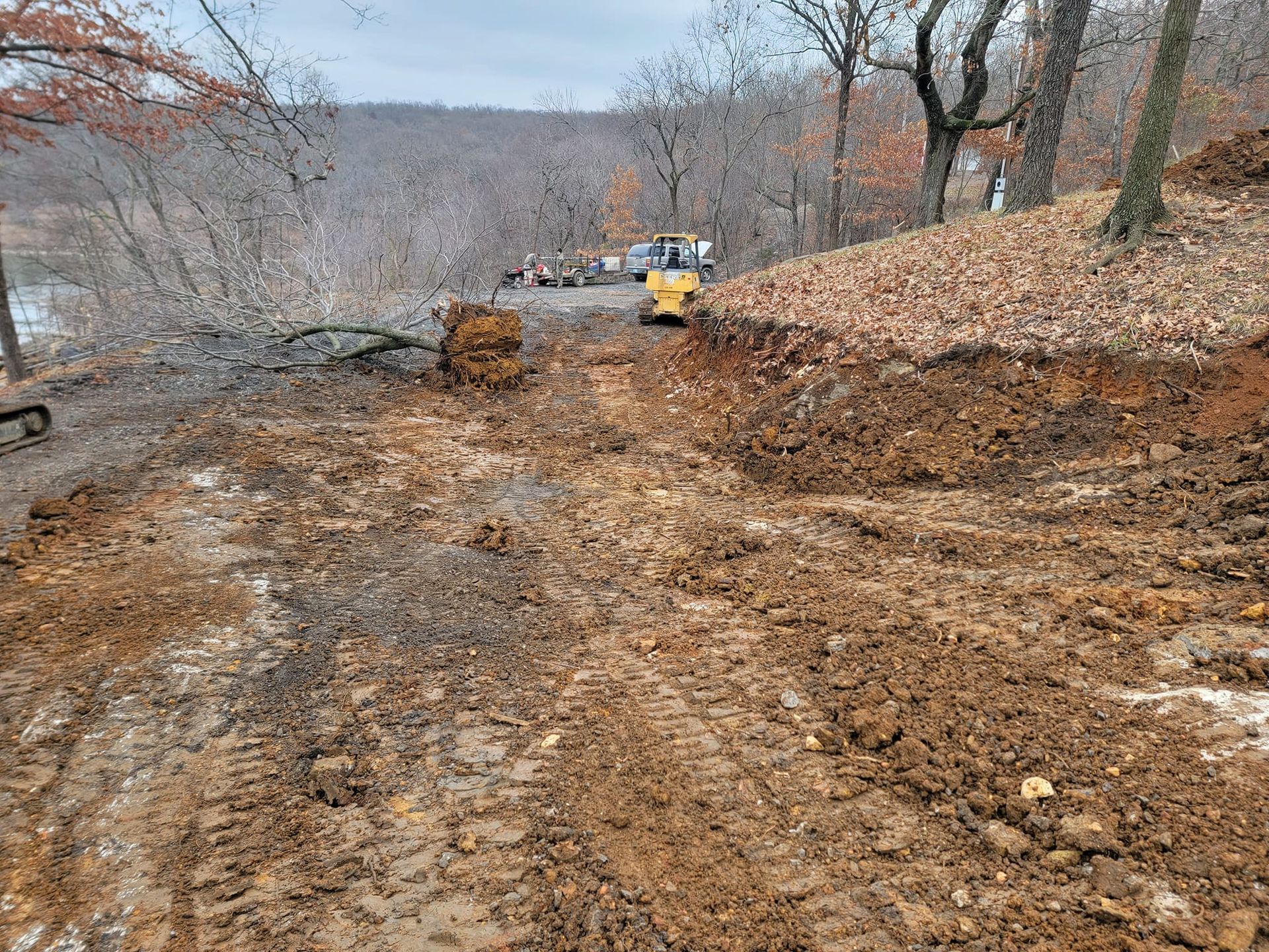 A bulldozer is driving down a dirt road in the woods.