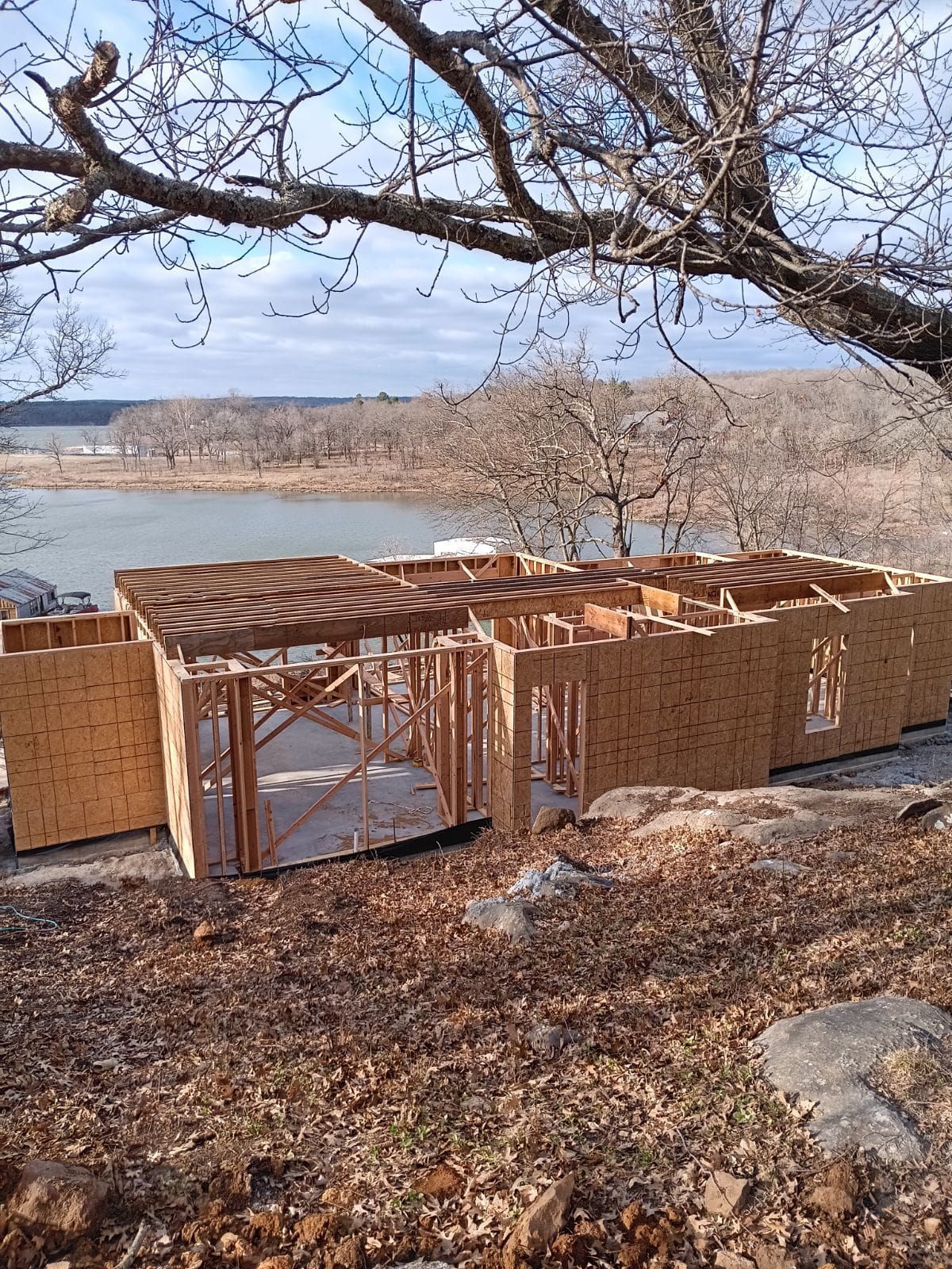 A house is being built on a hill overlooking a lake.