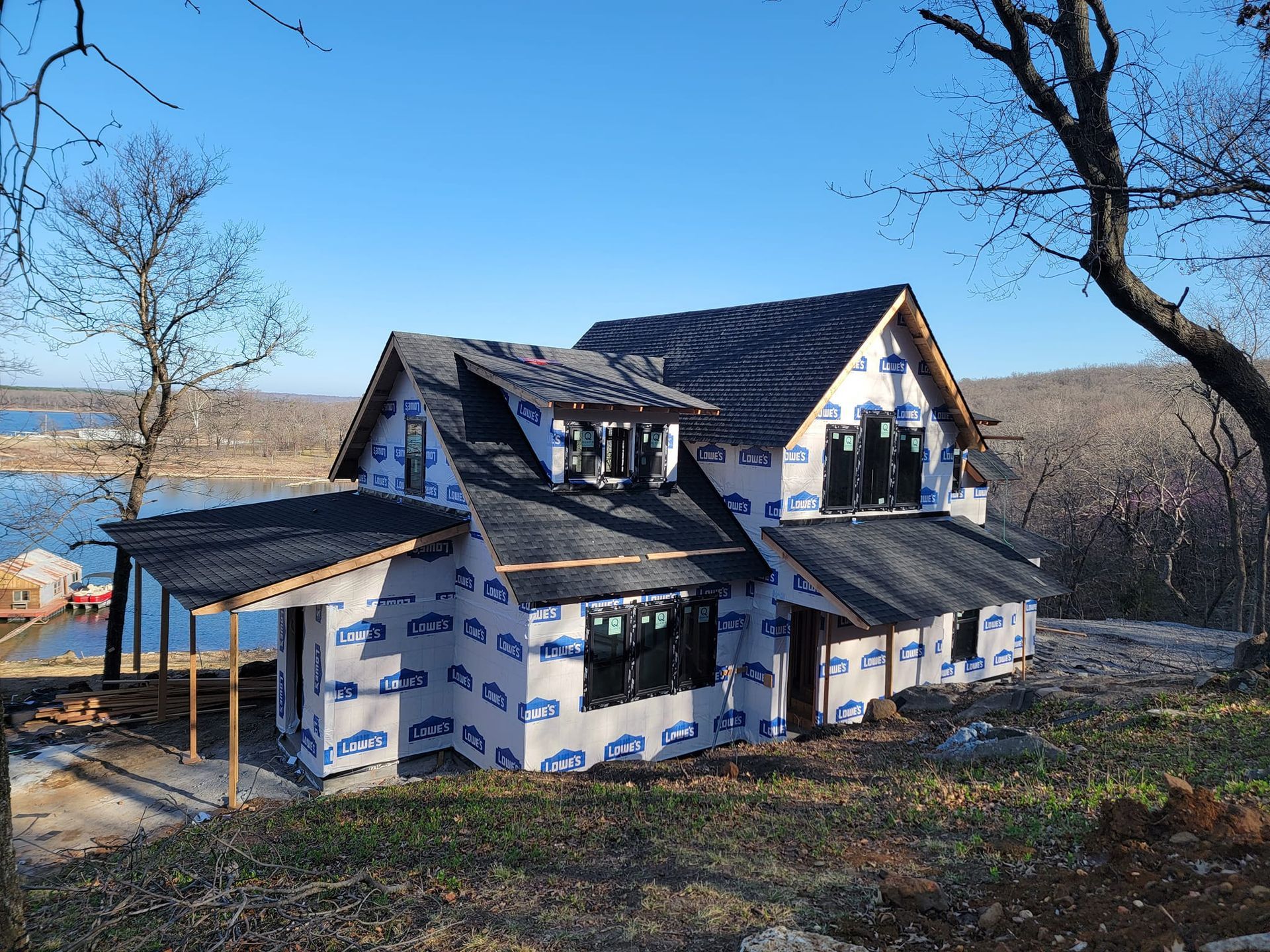 A house is being built on a hill overlooking a lake.