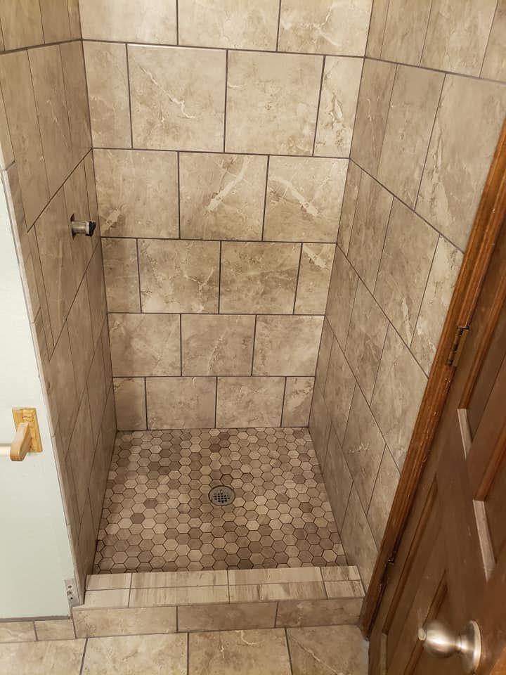 A bathroom with a tiled shower stall and a door.