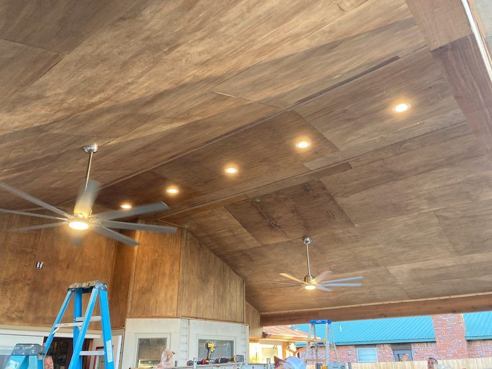 Wooden ceiling with recessed lights and ceiling fans. A-frame construction with a ladder and a partially built wall.