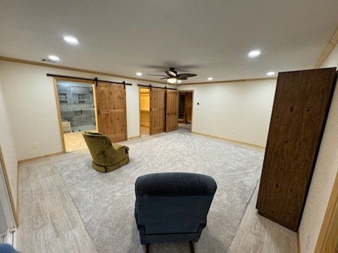 Spacious bedroom with gray carpet, two armchairs, wood-paneled doors, and recessed lighting.