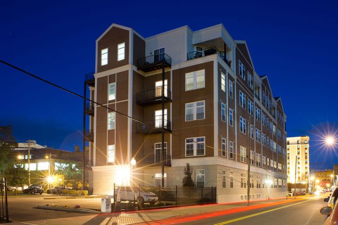 A large brick building with a lot of windows is lit up at night