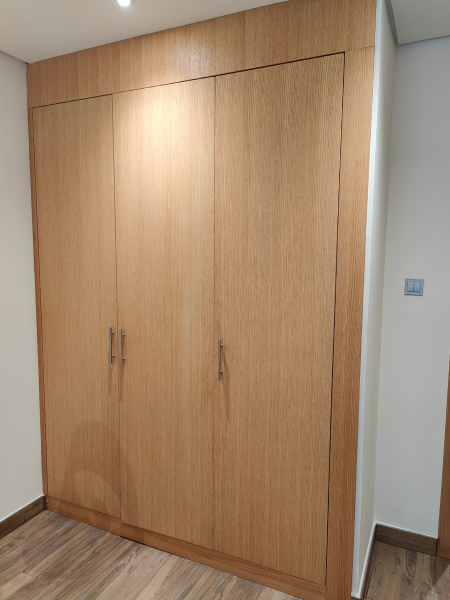 Wooden built-in wardrobe with two doors in a white-walled room