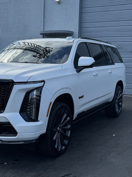 White SUV parked beside a building, front-left view, with tinted windows and black wheels