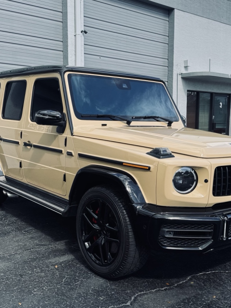 Beige Mercedes-Benz G-Class SUV parked outside a gray building